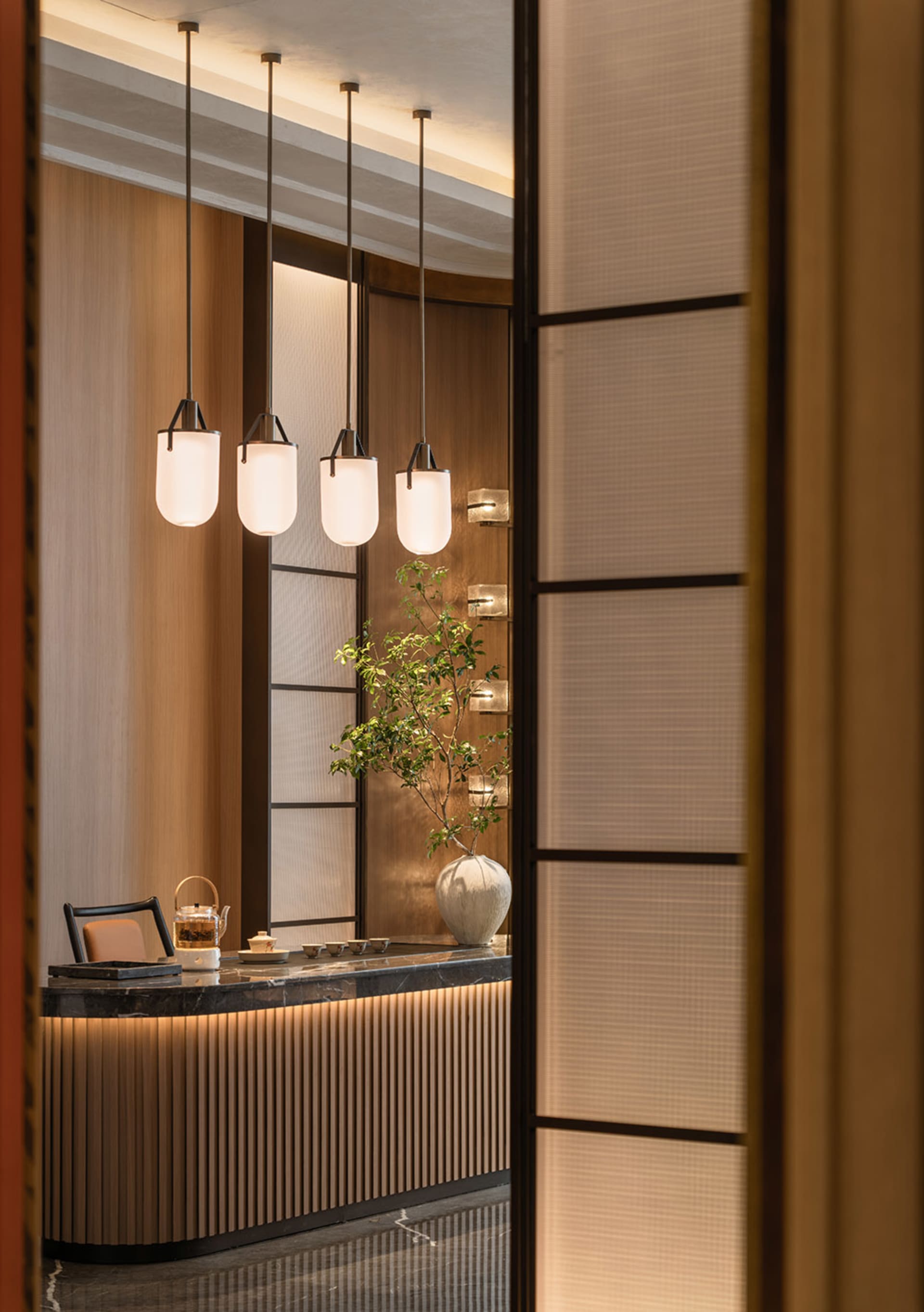 A modern tea room with wooden accents, marble table, and glass pendant lights.