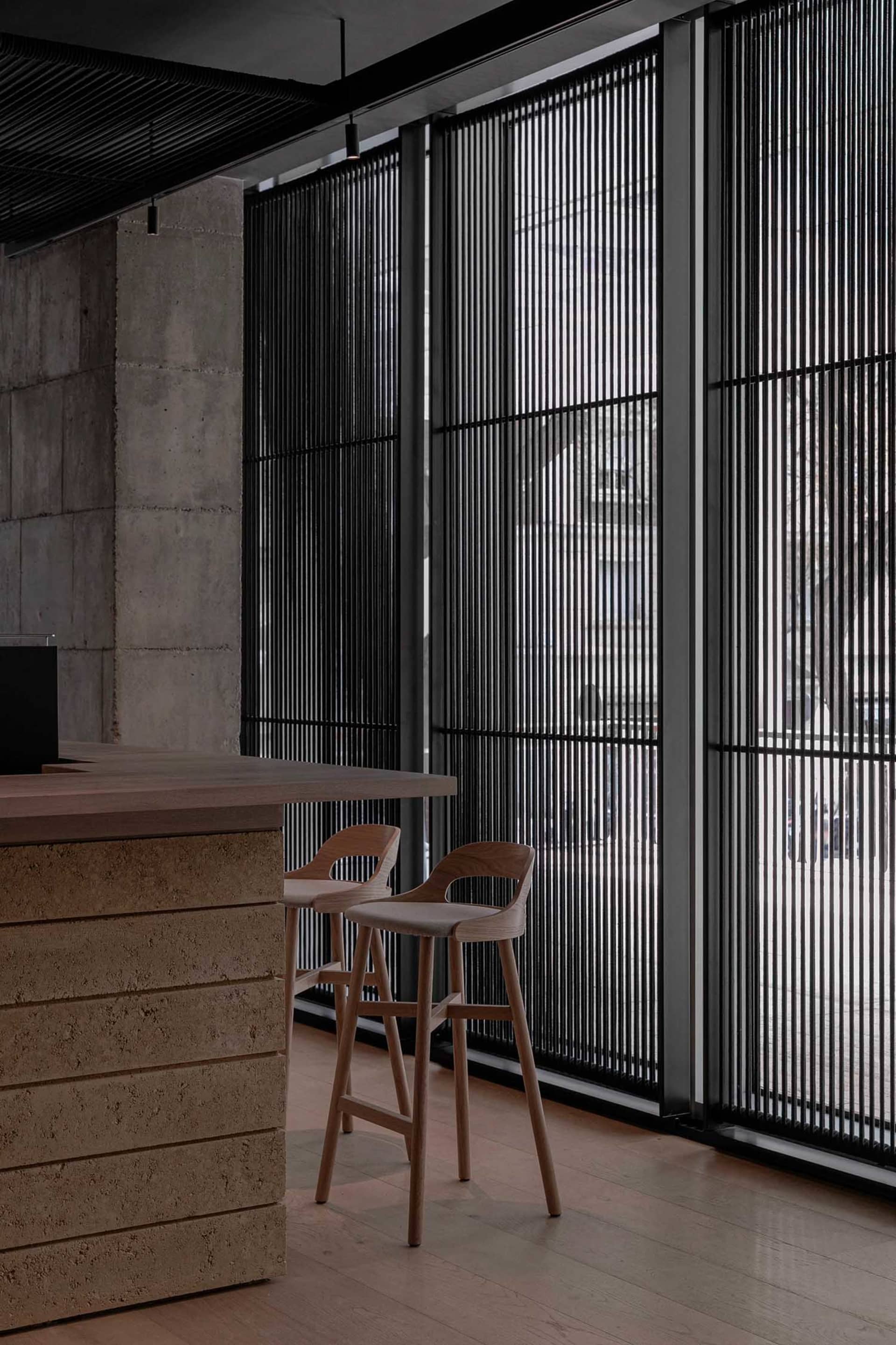 Modern industrial-style bar and restaurant interior with concrete, wood, and glass elements.