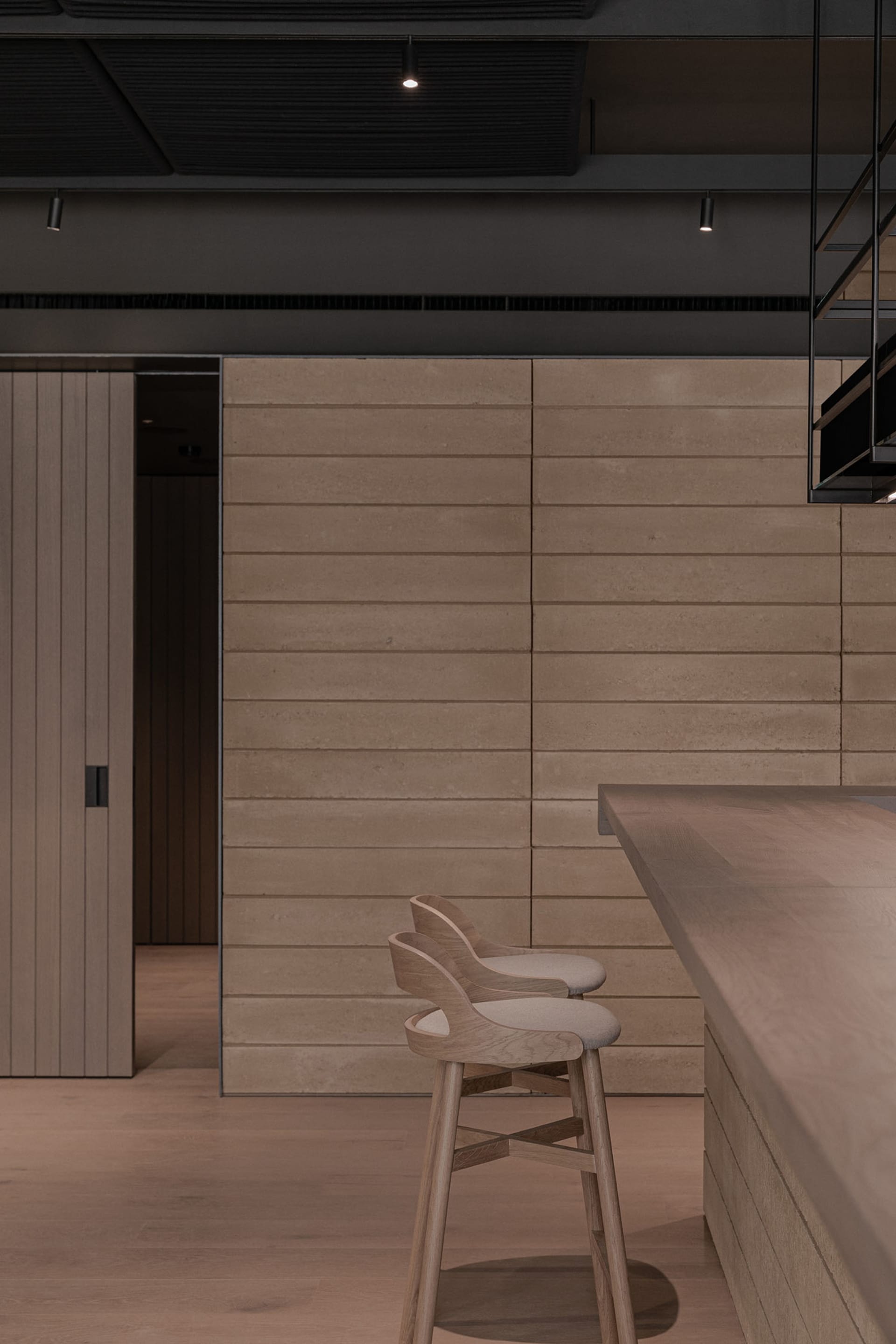 A modern industrial kitchen bar with wooden stools and a concrete countertop.