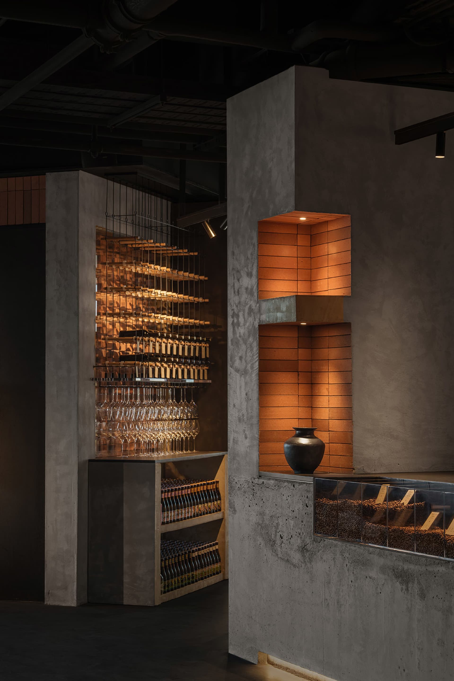 Industrial design restaurant interior with concrete shelves and illuminated brick wall feature.