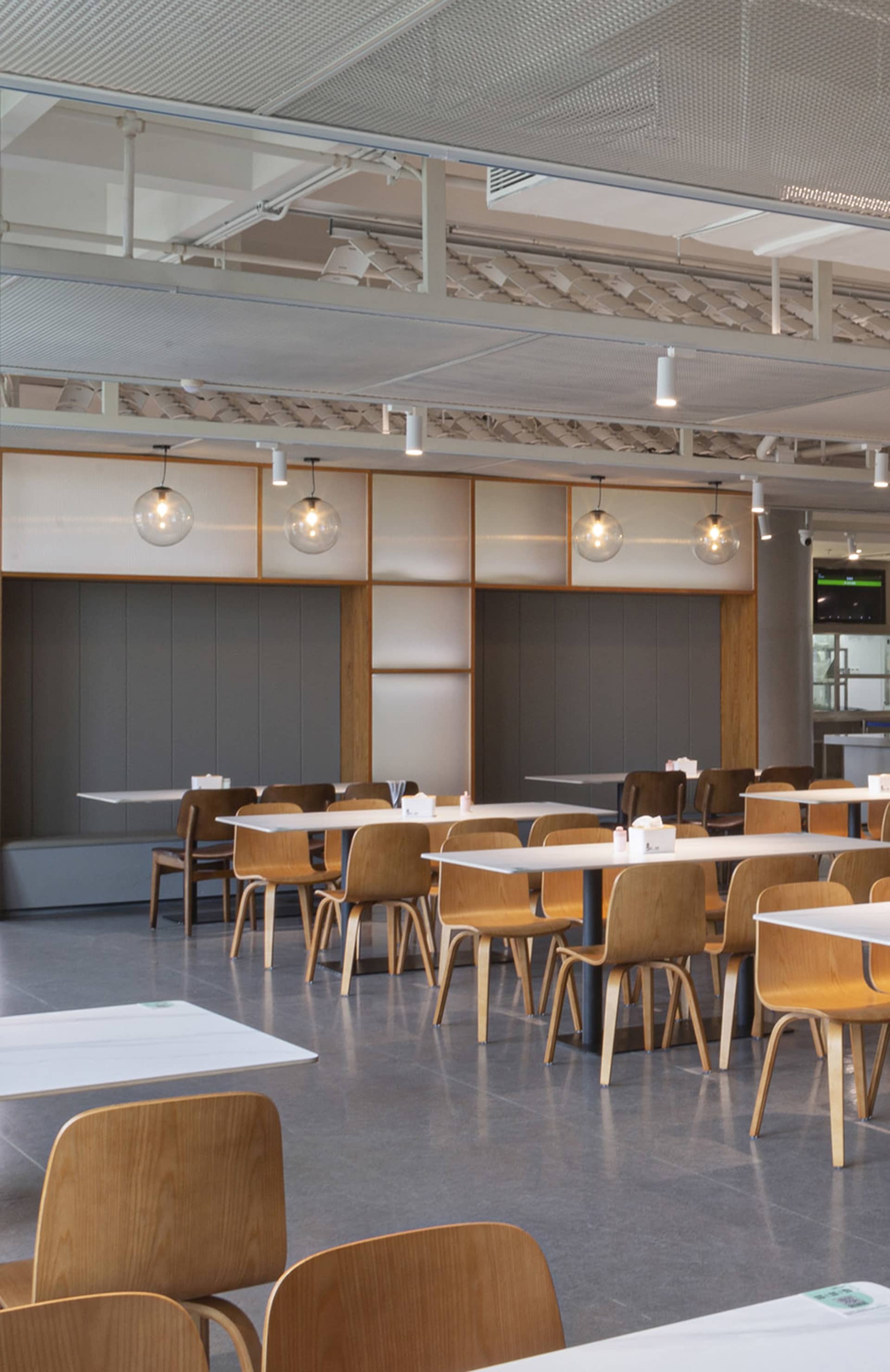 A spacious, industrial-style restaurant interior featuring timber furniture and white tables and chairs.