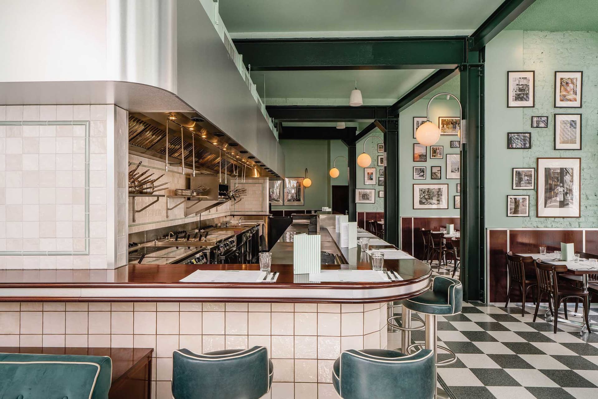 A restaurant interior featuring a tile-walled bar with brass accents and concrete countertops.