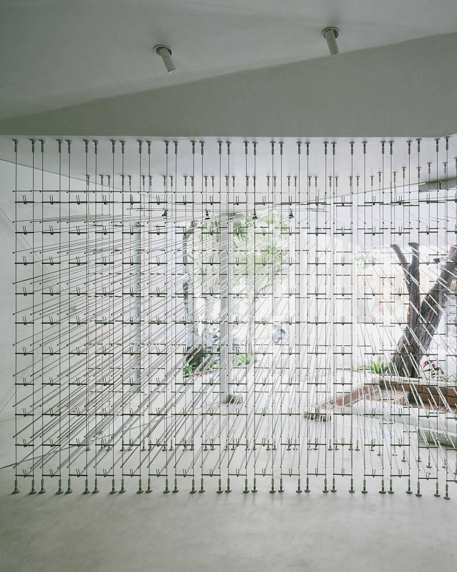 A modern art installation featuring a grid of metal wires and fasteners.
