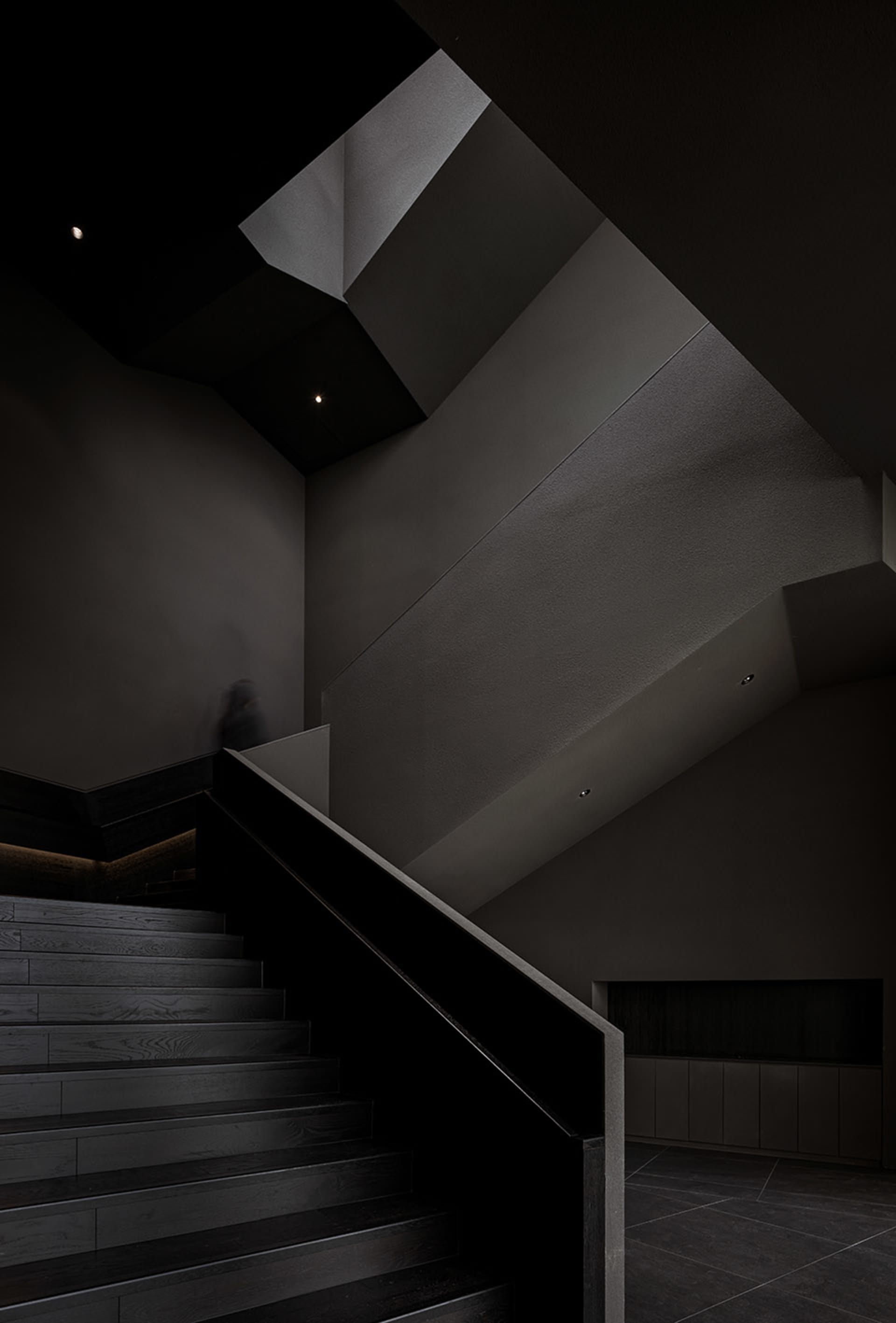 A modern interior space with black metal stairs and railings, featuring a minimalist design and dark walls.