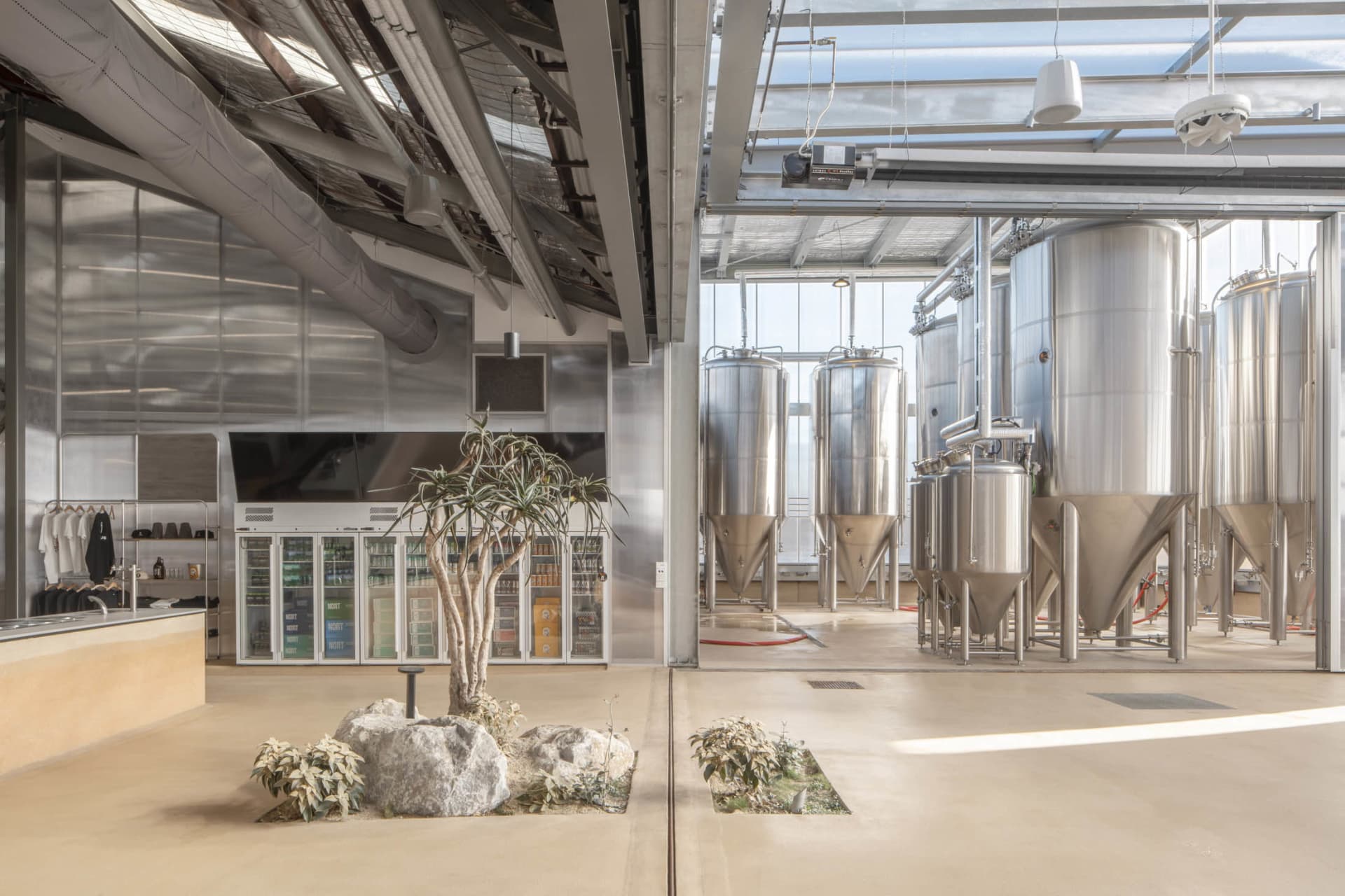 Industrial-style indoor brewery with polished concrete flooring, stainless steel brewing tanks, and a minimalist interior des
