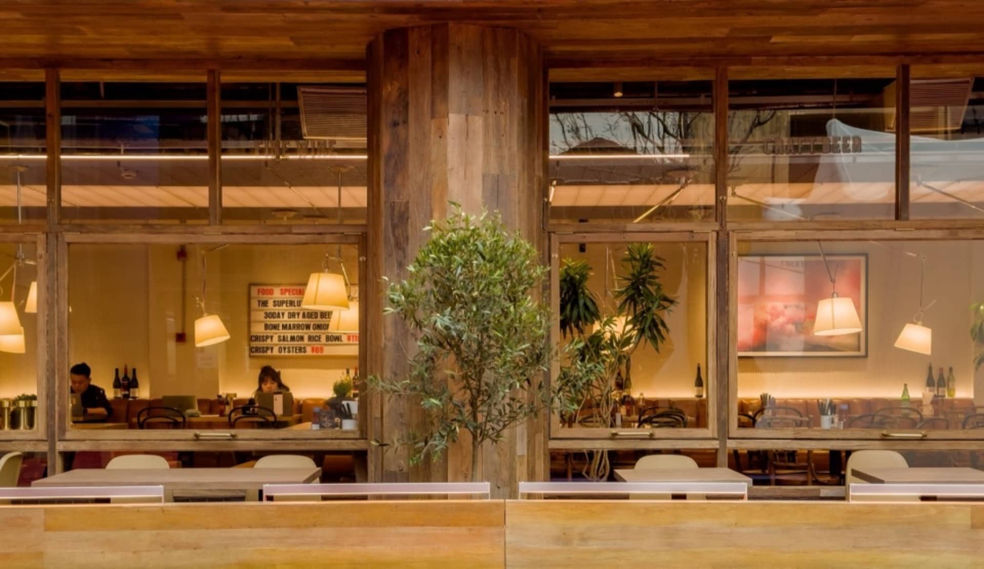 A rustic, industrial-themed restaurant interior with wooden accents and greenery.