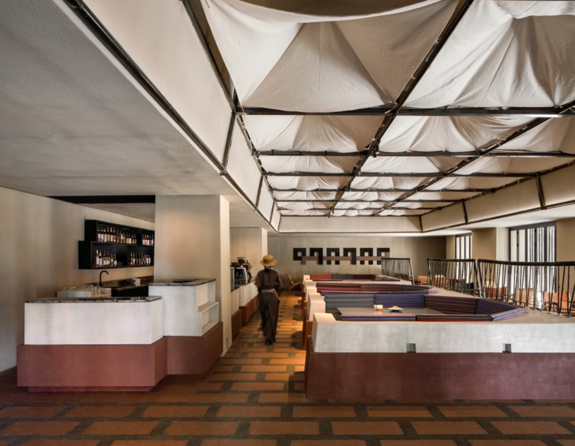 A modern restaurant bar with concrete flooring, textile ceiling, and wood accents.