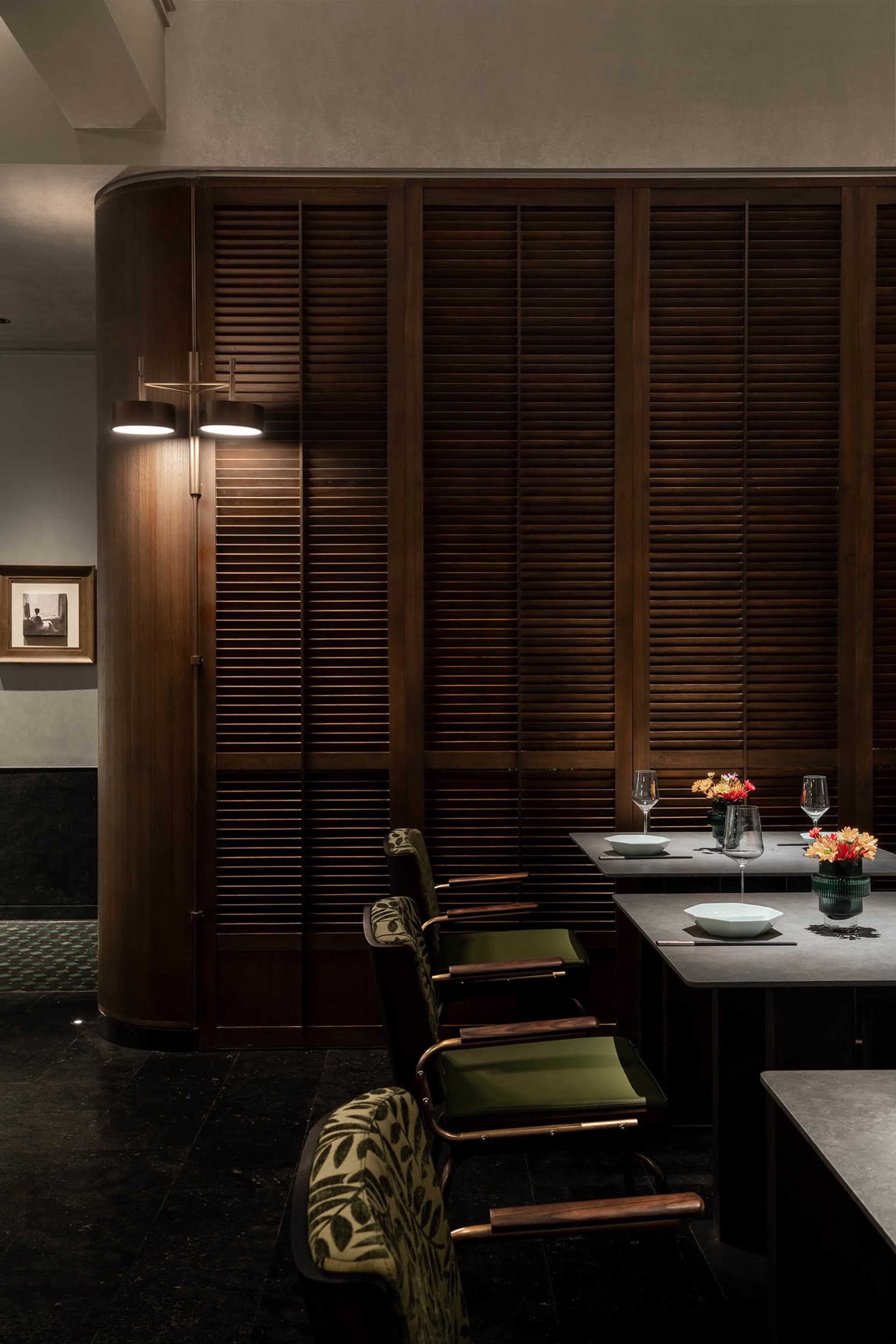 A modern restaurant interior with wooden elements, including a wooden wall and chairs, and a table set for dining.