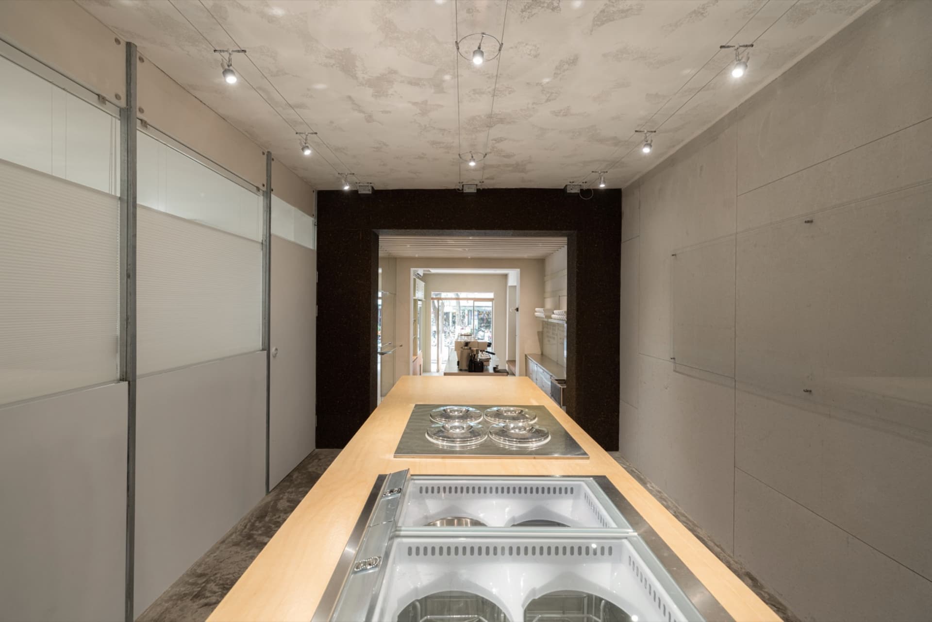 Modern retail environment with a metal countertop featuring espresso machines.