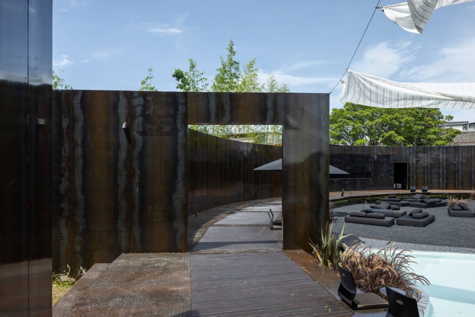 Modern, industrial-style backyard garden featuring metallic walls and green plants.