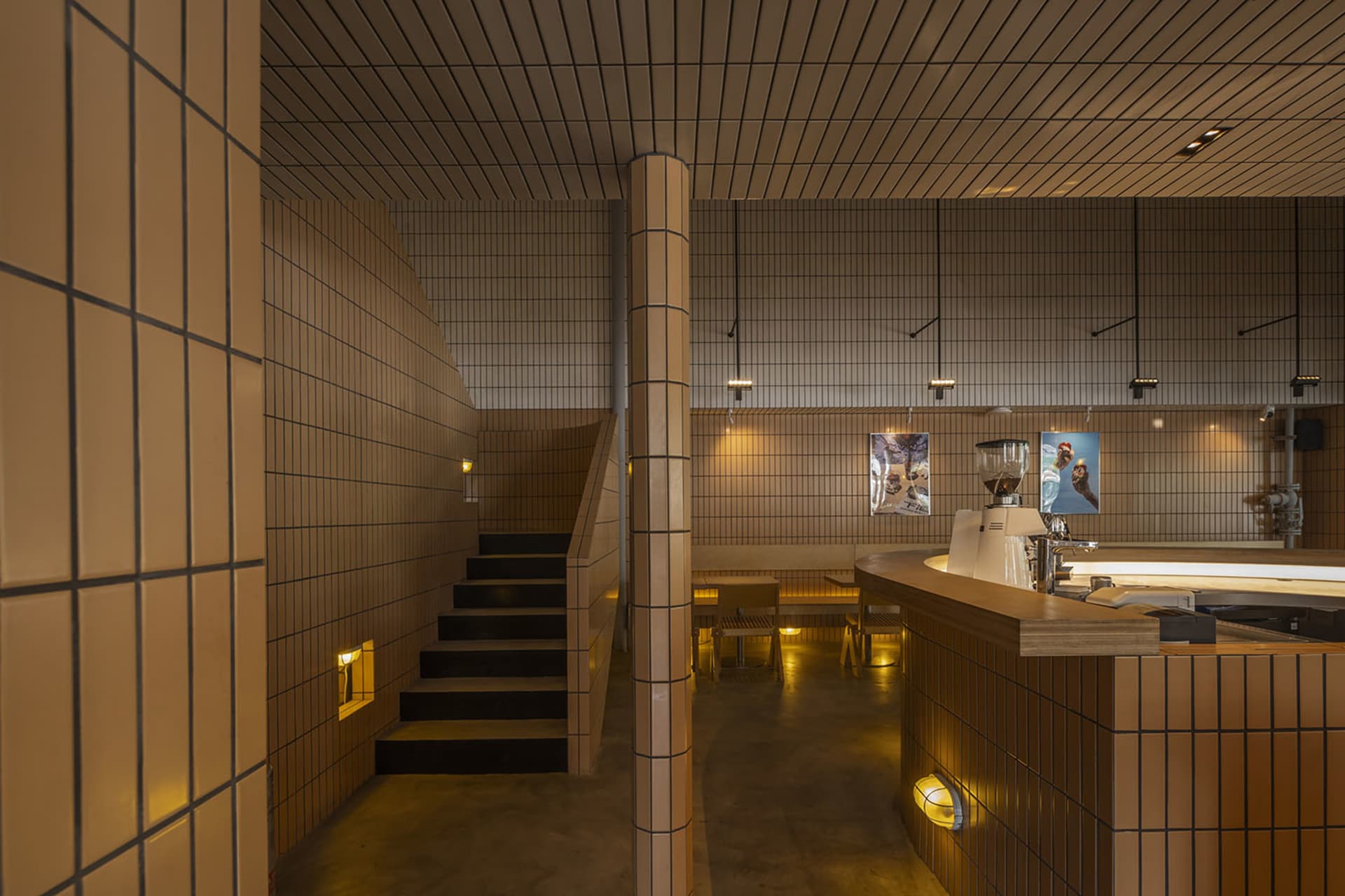 Interior view of a modern coffee shop with tile walls and concrete elements