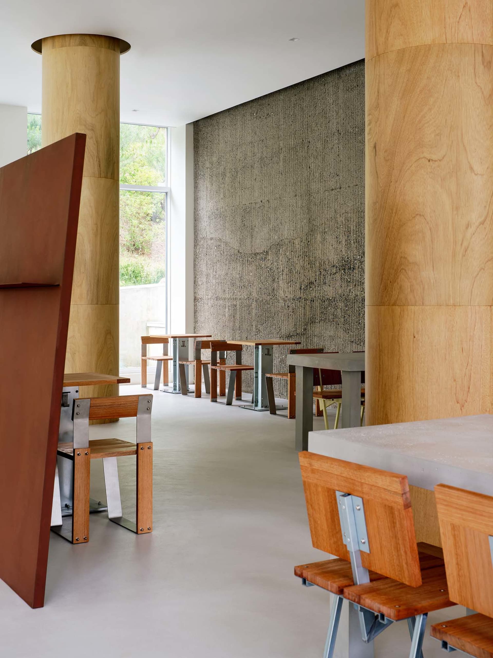 A modern industrial restaurant featuring wooden tables and concrete floor and walls.