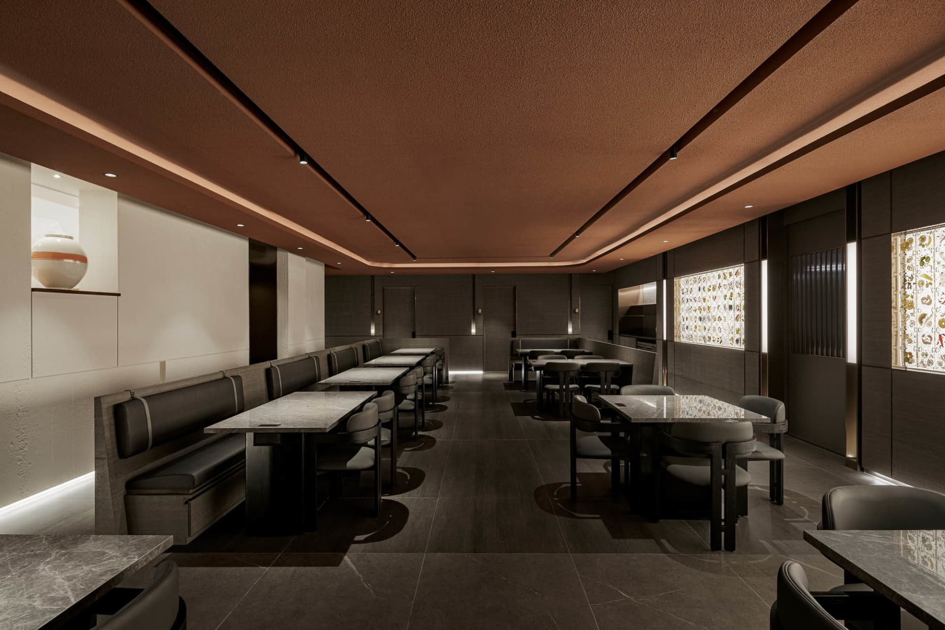 Modern restaurant interior featuring marble countertops, leather seating, and wooden furniture.