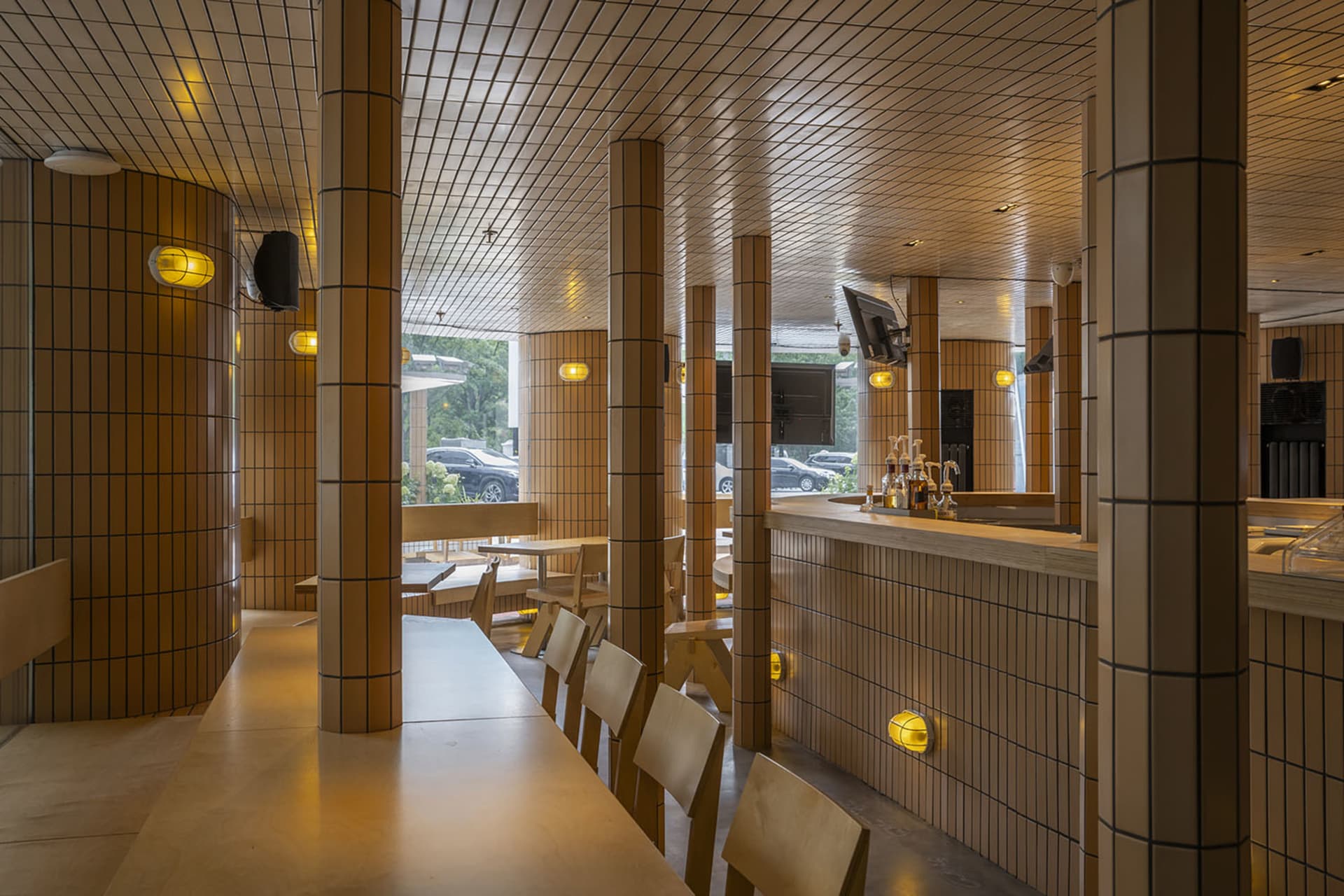 Interior view of a modern restaurant featuring tiled walls and wooden furniture.