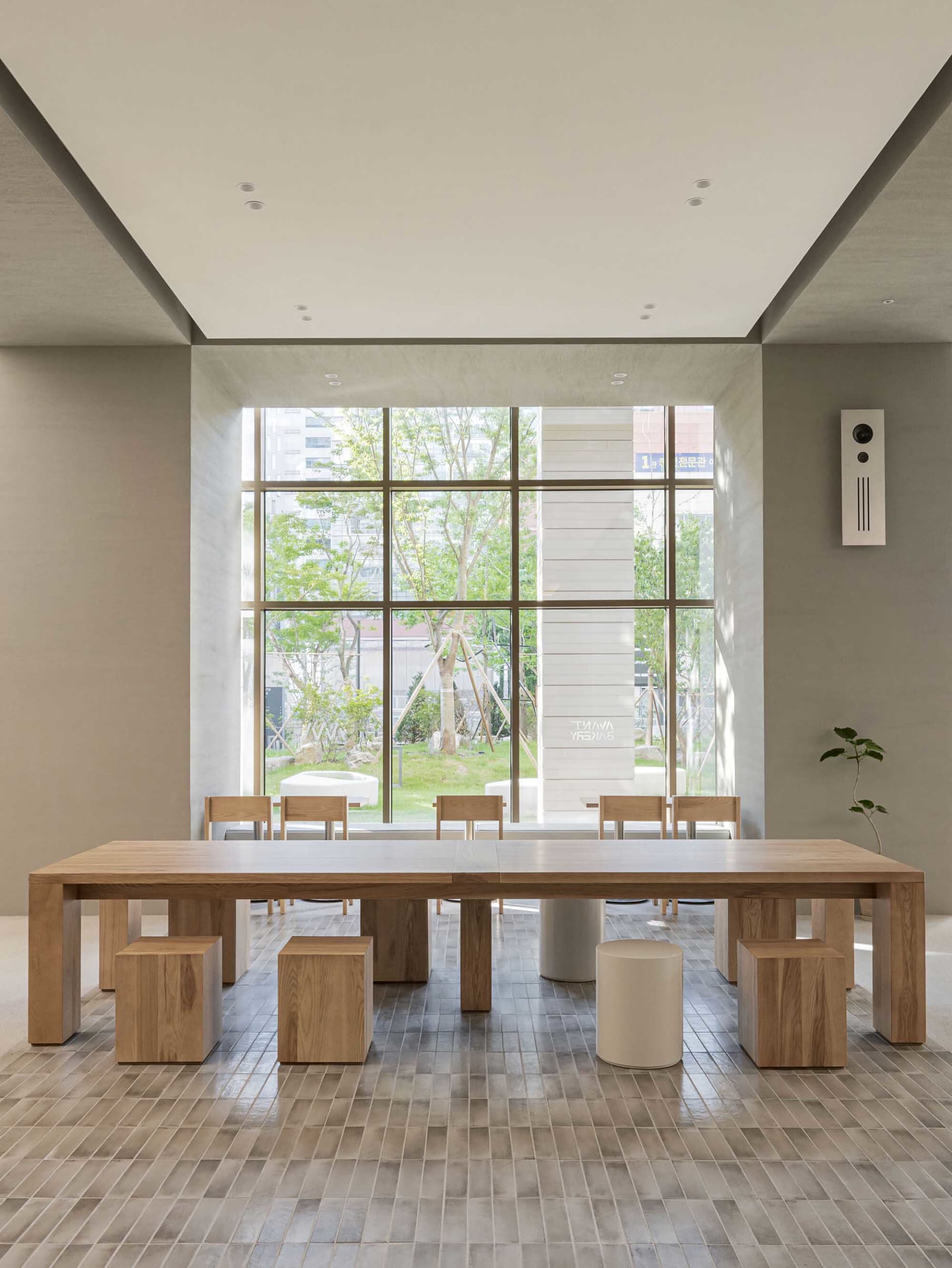 Minimalist design restaurant and lounge area with wooden furniture, concrete accents, and a large window