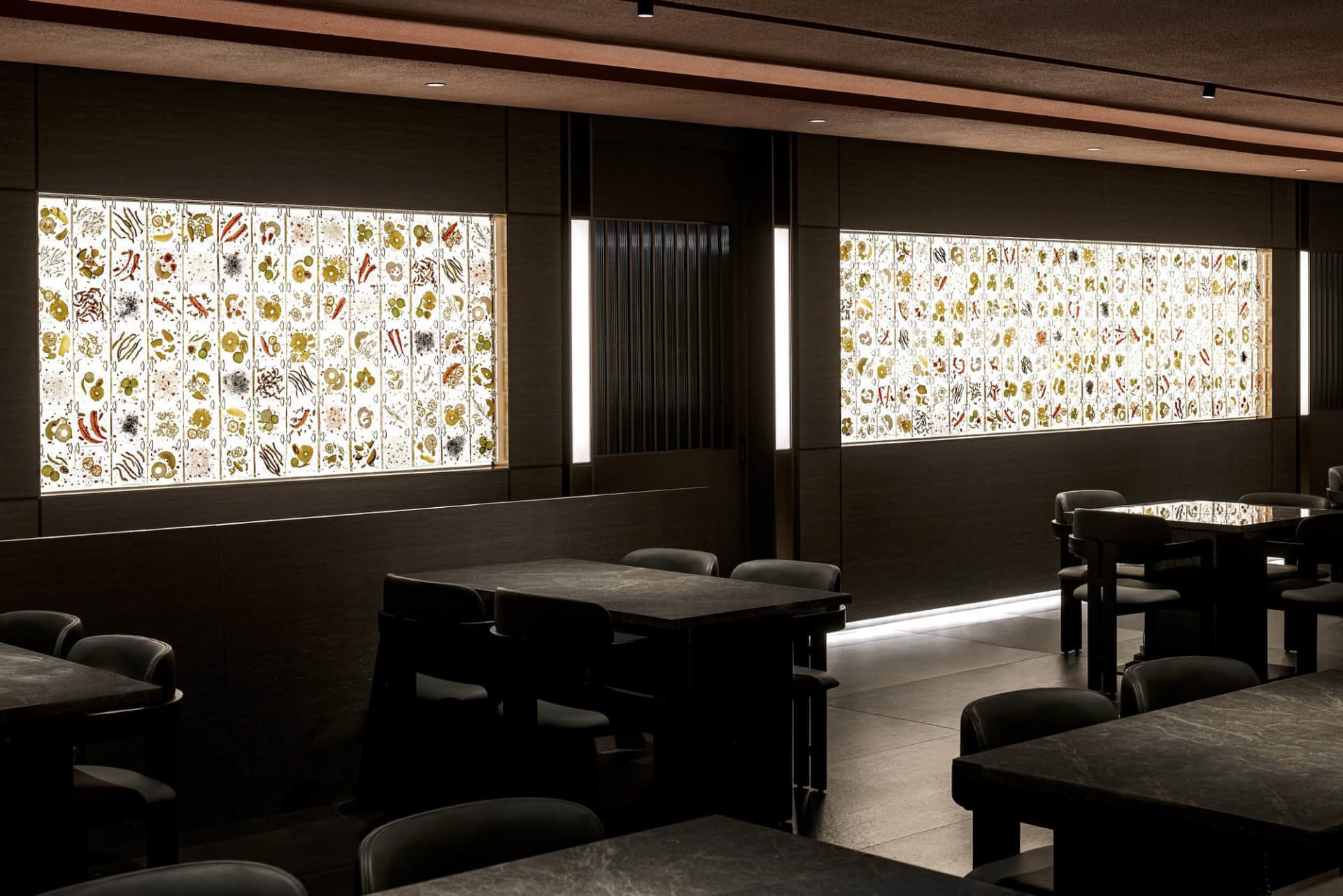 A restaurant interior with illuminated glass panels featuring intricate patterns and designs.