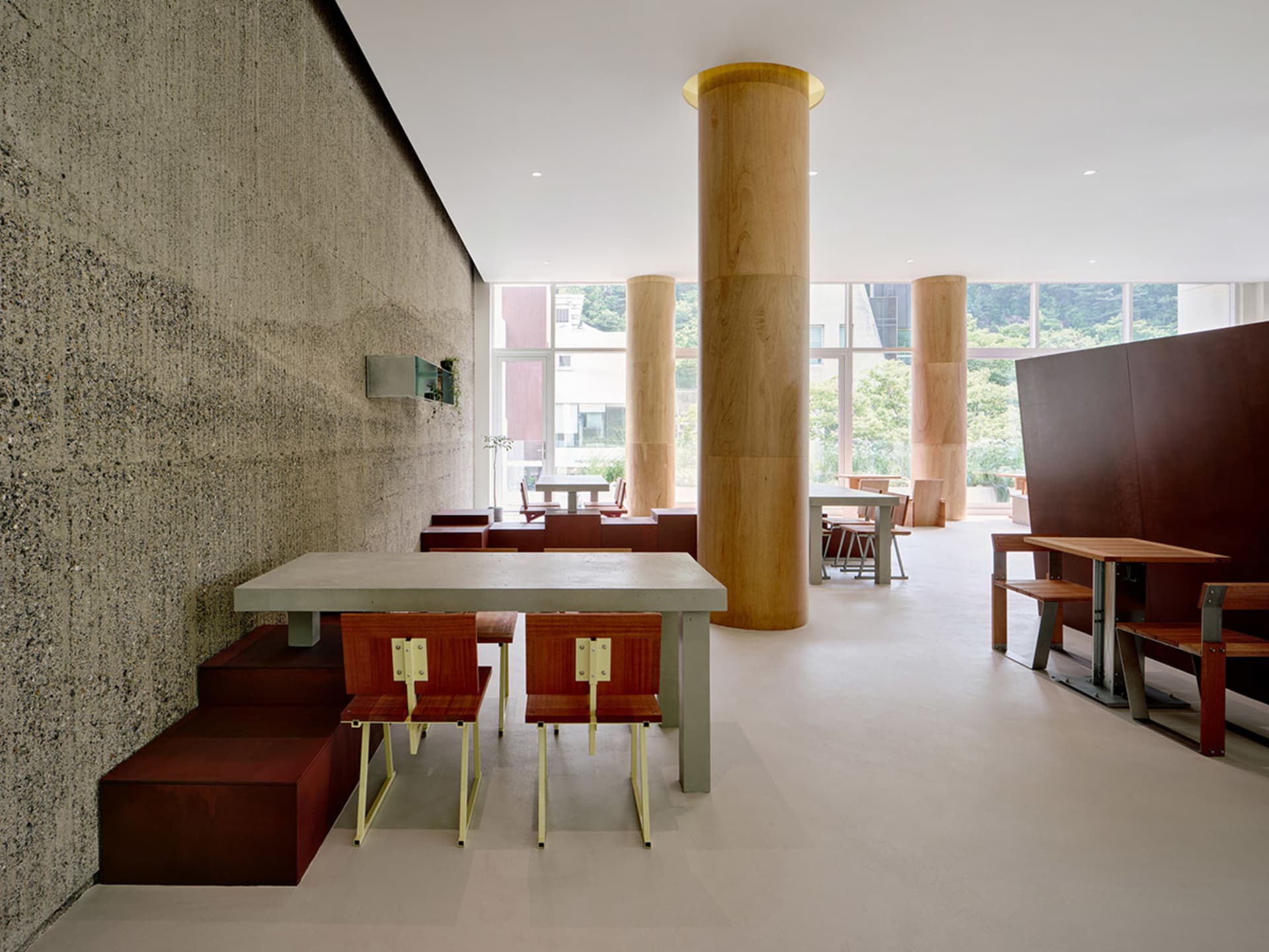 A stylish modern coffee shop with concrete walls, wooden tables, and steel furniture.