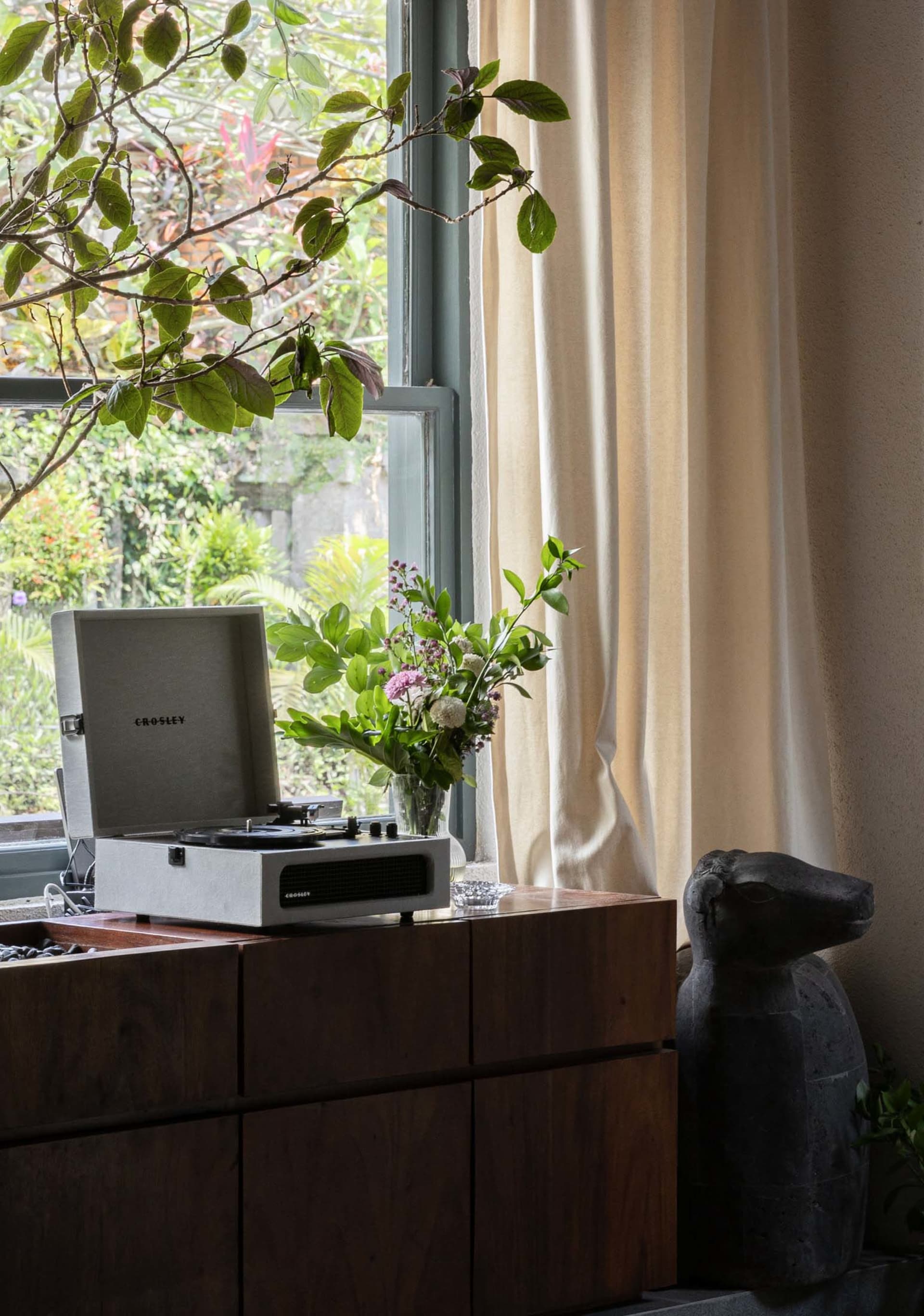 A modern living room with a plant on a window sill and a wooden cabinet.