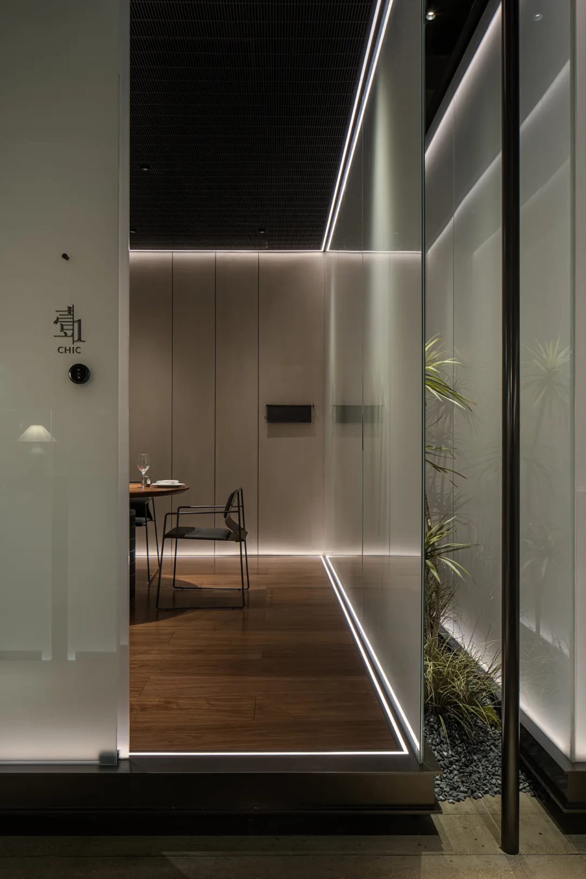 Modern restaurant interior with a minimalist design featuring metal lighting and sleek furniture.
