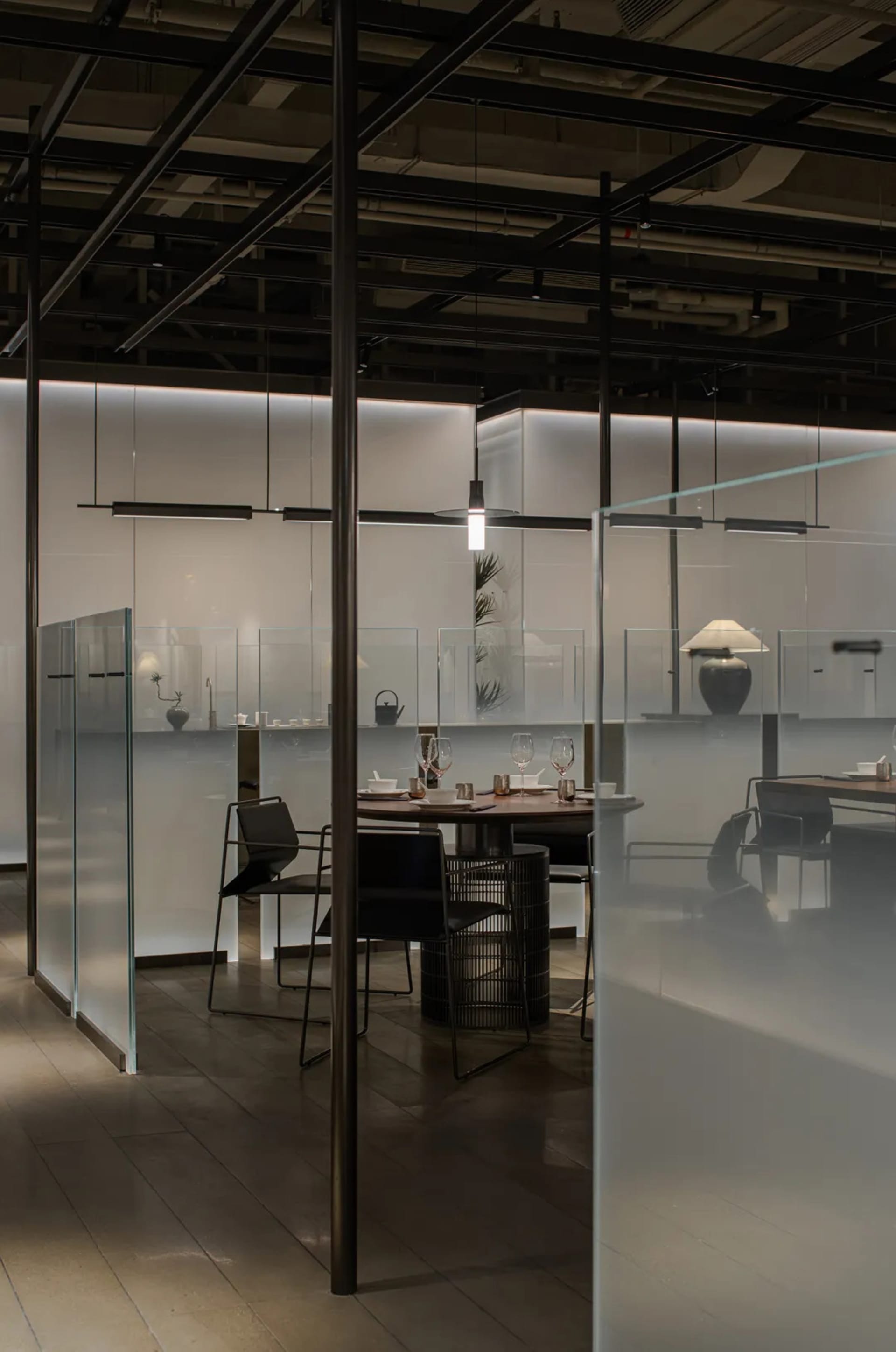 Modern restaurant interior with frosted glass panel walls and industrial-style furnishings.