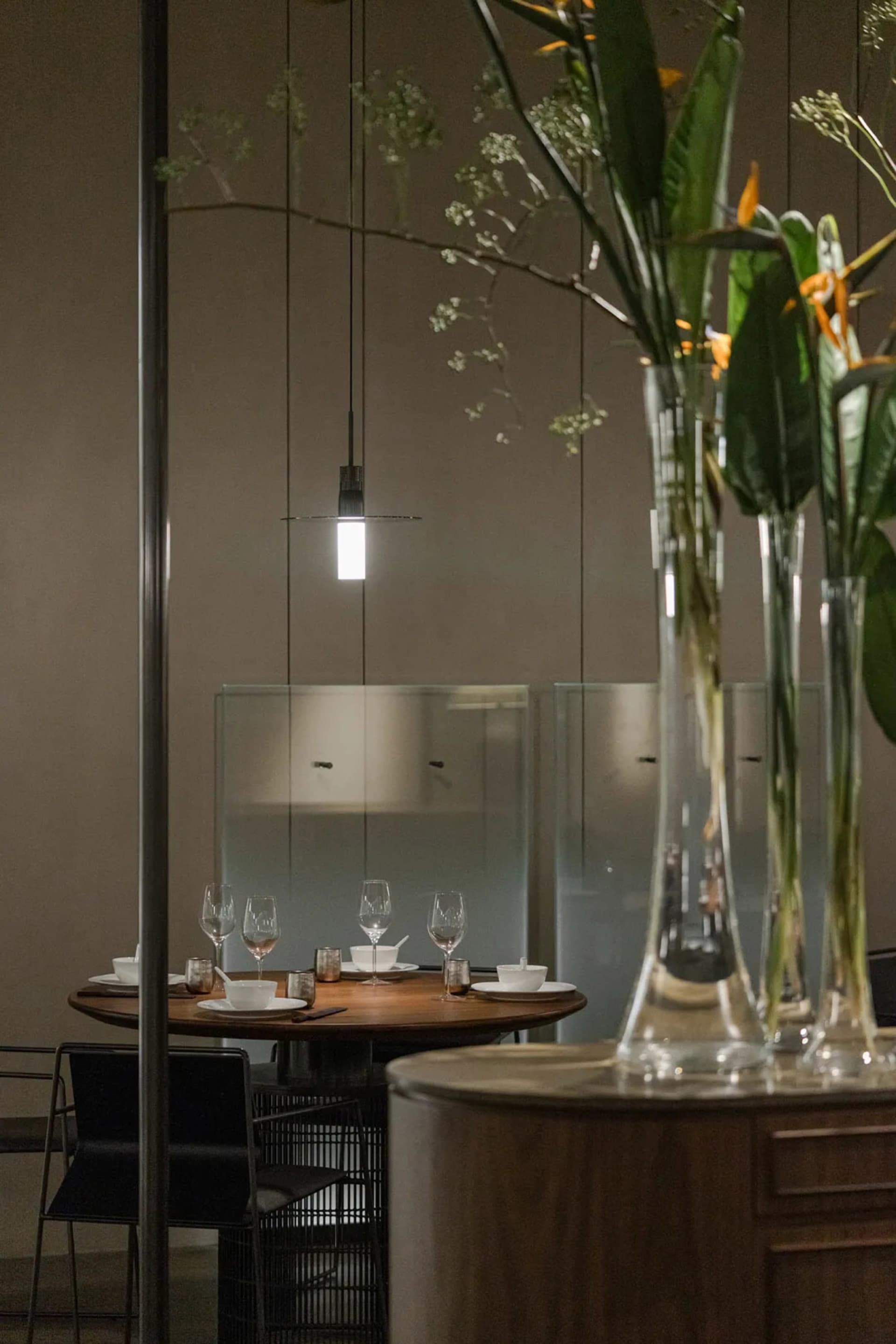 A modern restaurant interior featuring wooden tables, glass pendant lights, and metal accents.