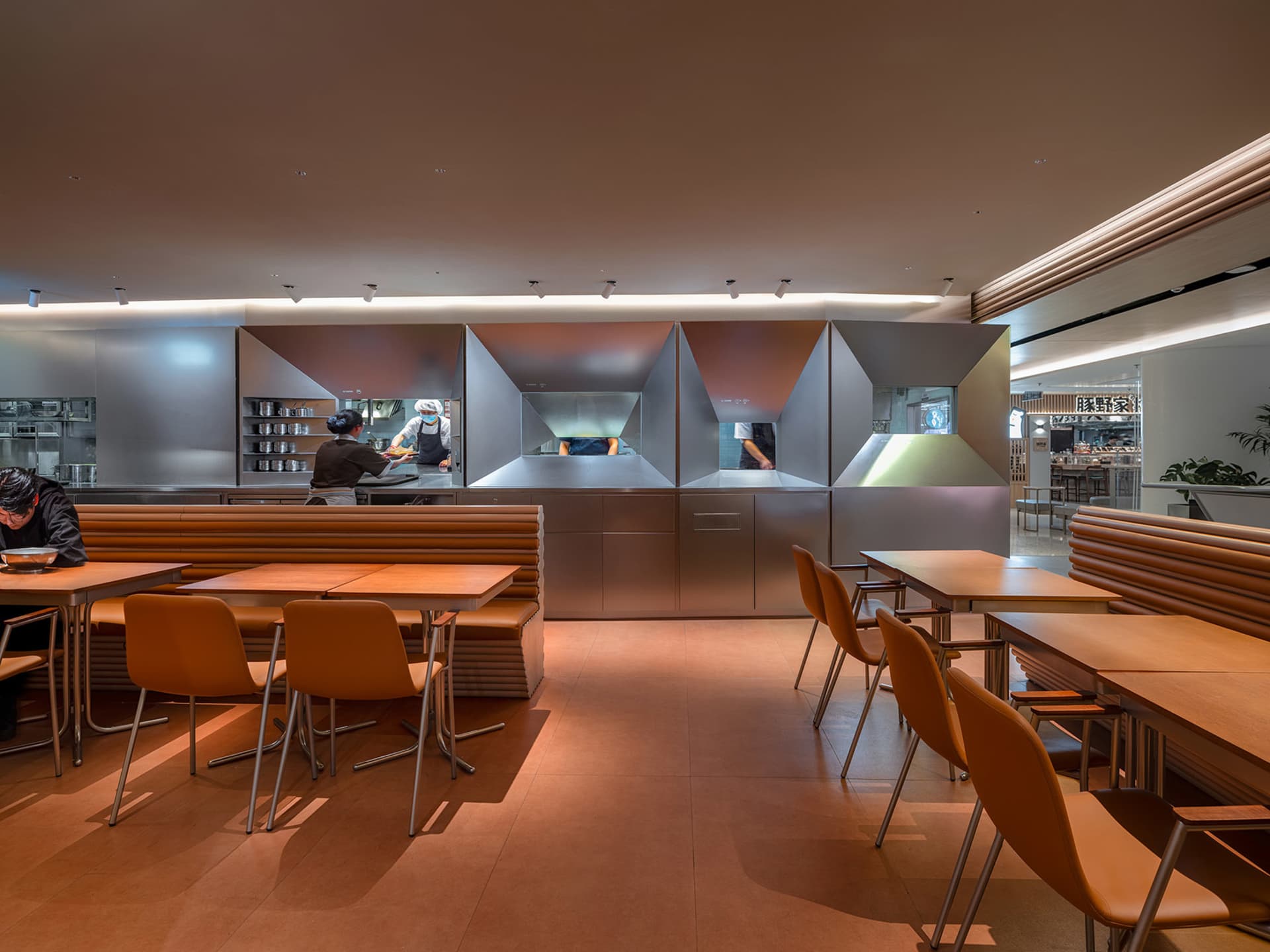 Industrial-style restaurant kitchen with metal tiles and open seating area.