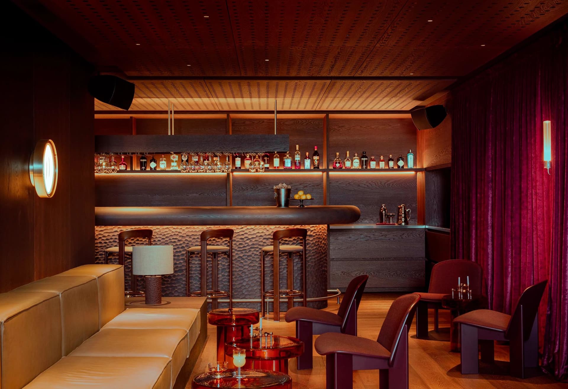 Modern bar interior featuring wooden bar top, leather seating, and metal accents.