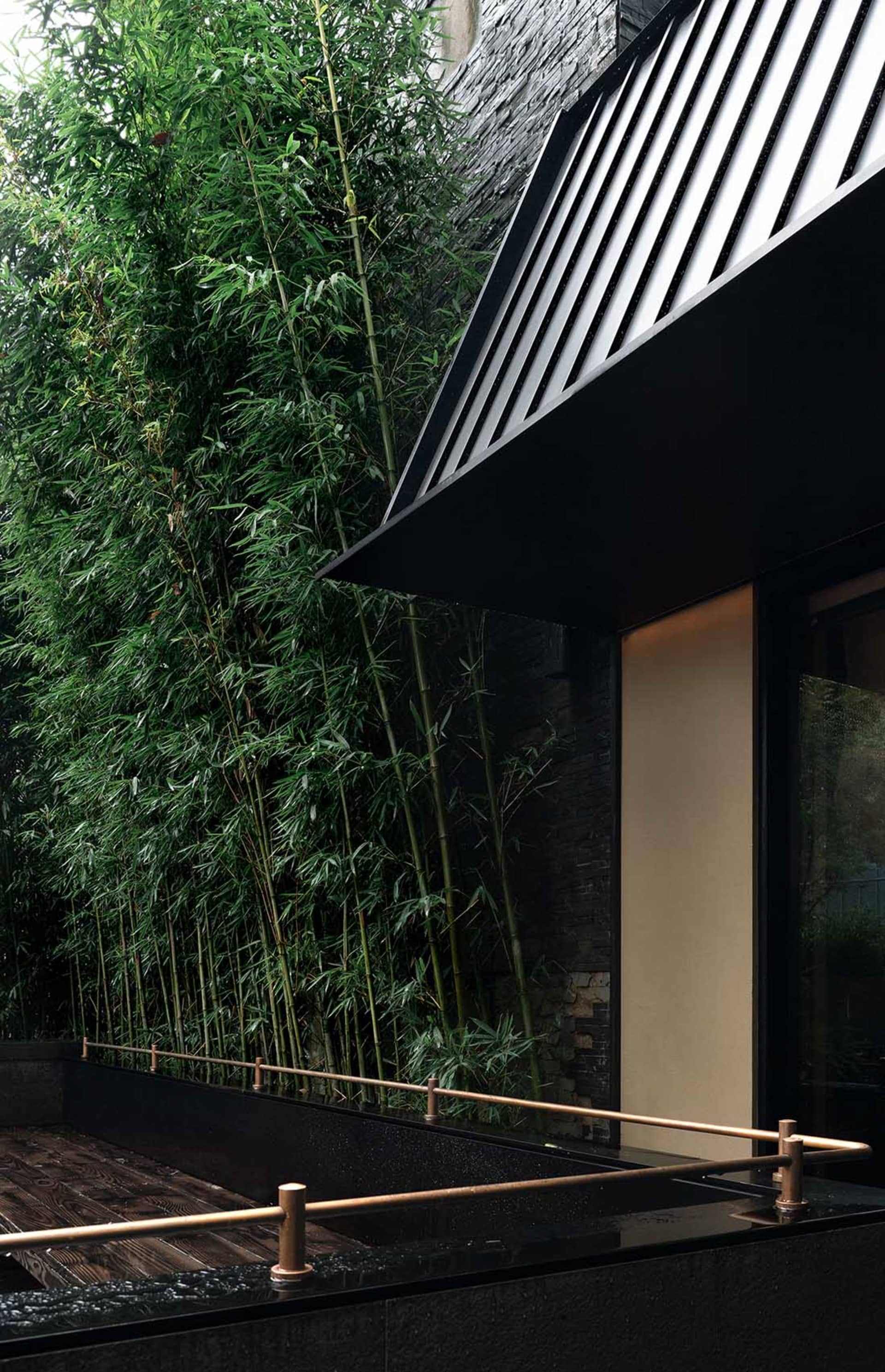 A modern exterior featuring bamboo and glass walls, and concrete flooring.