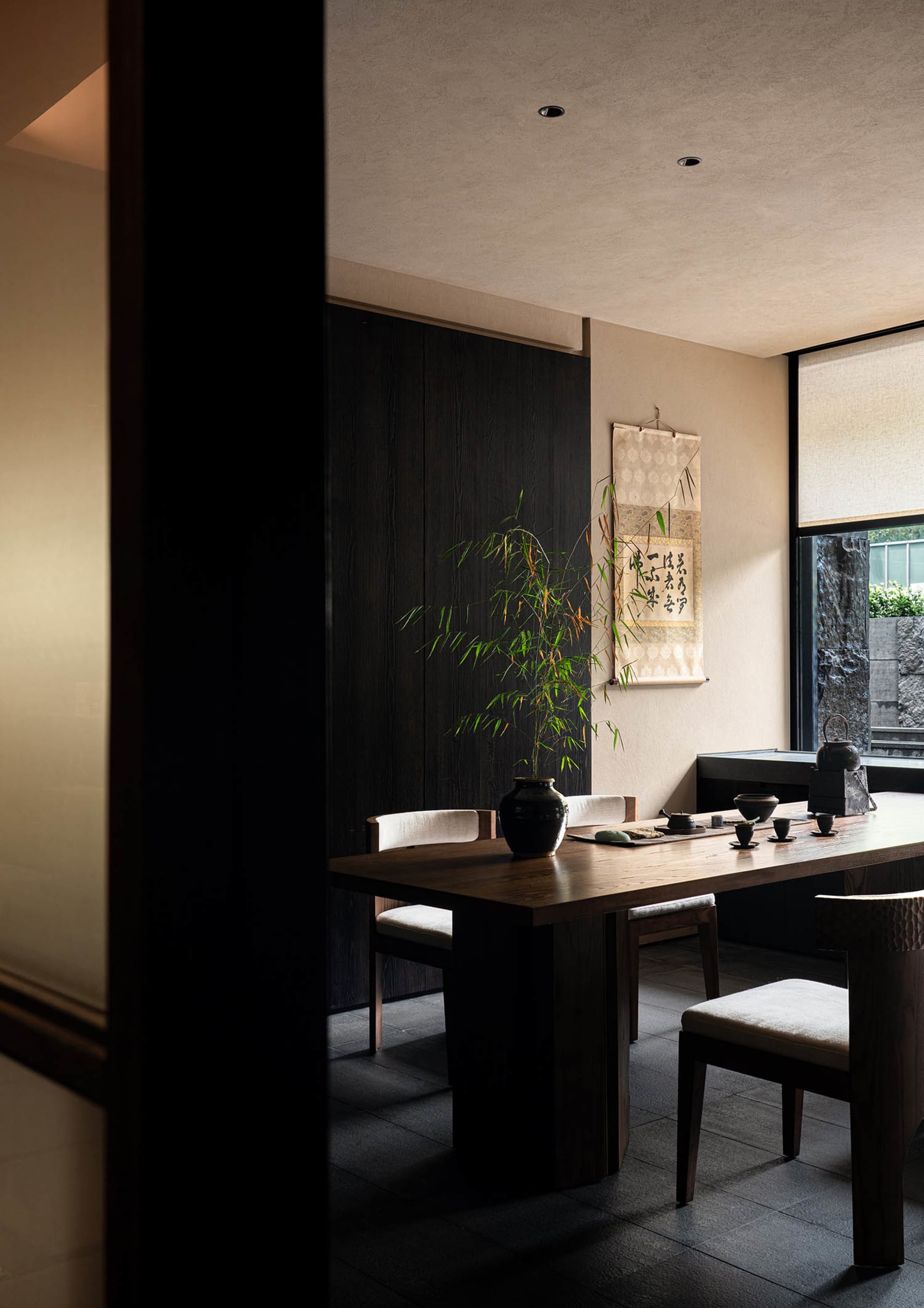 A modern table setting featuring wooden table with fabric chairs and a plant decoration.