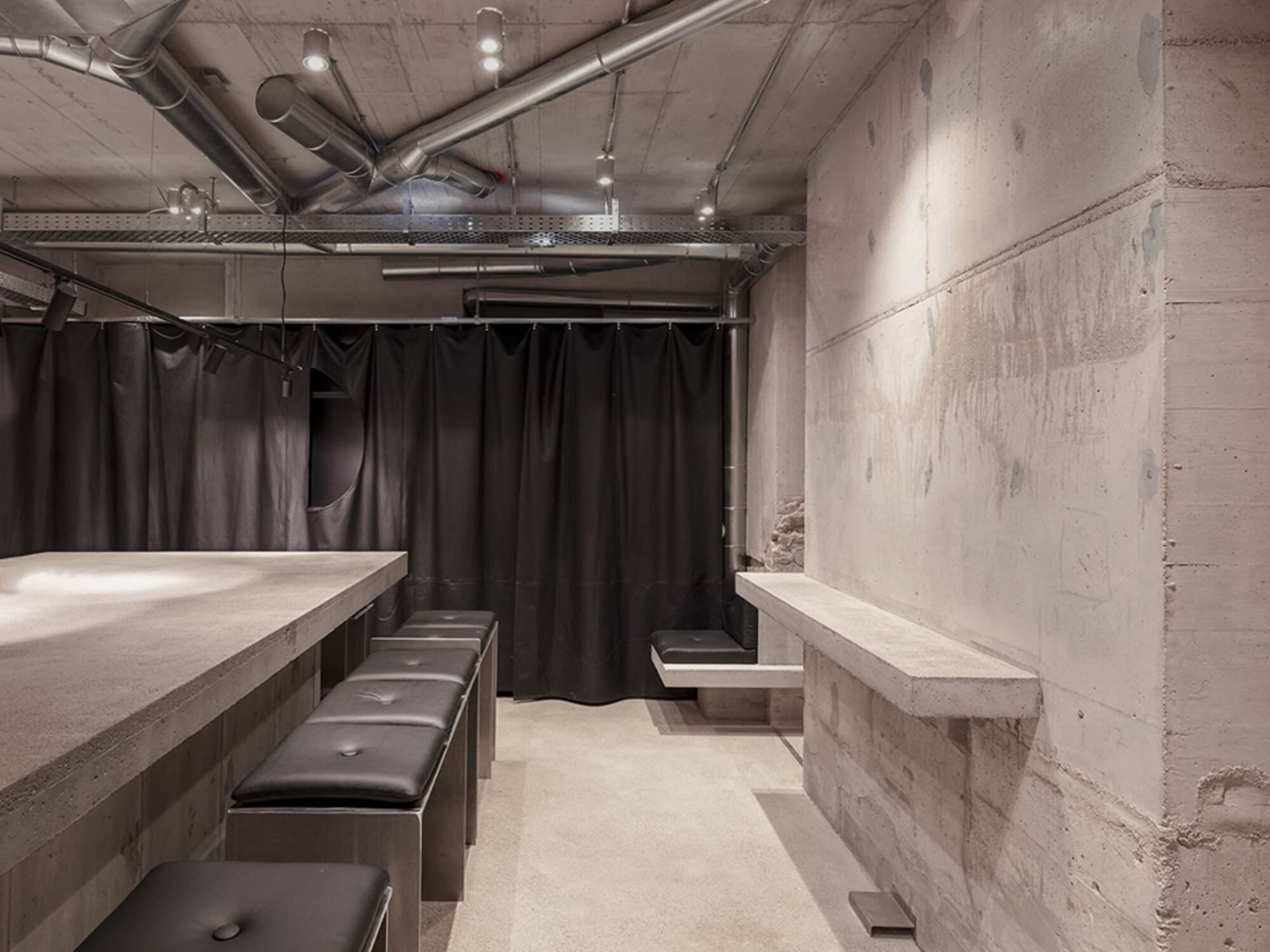Concrete basement bar with seating and industrial design elements.