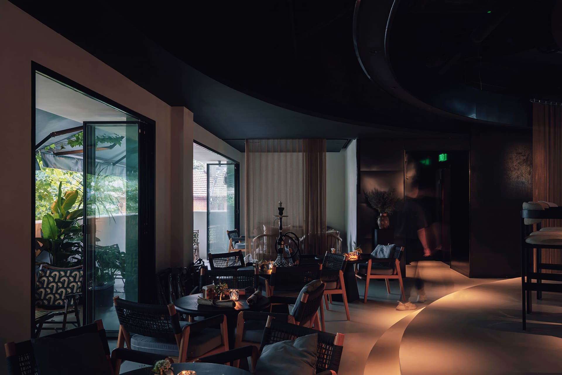 Modern restaurant interior with wooden furniture, glass walls, and metal accents.