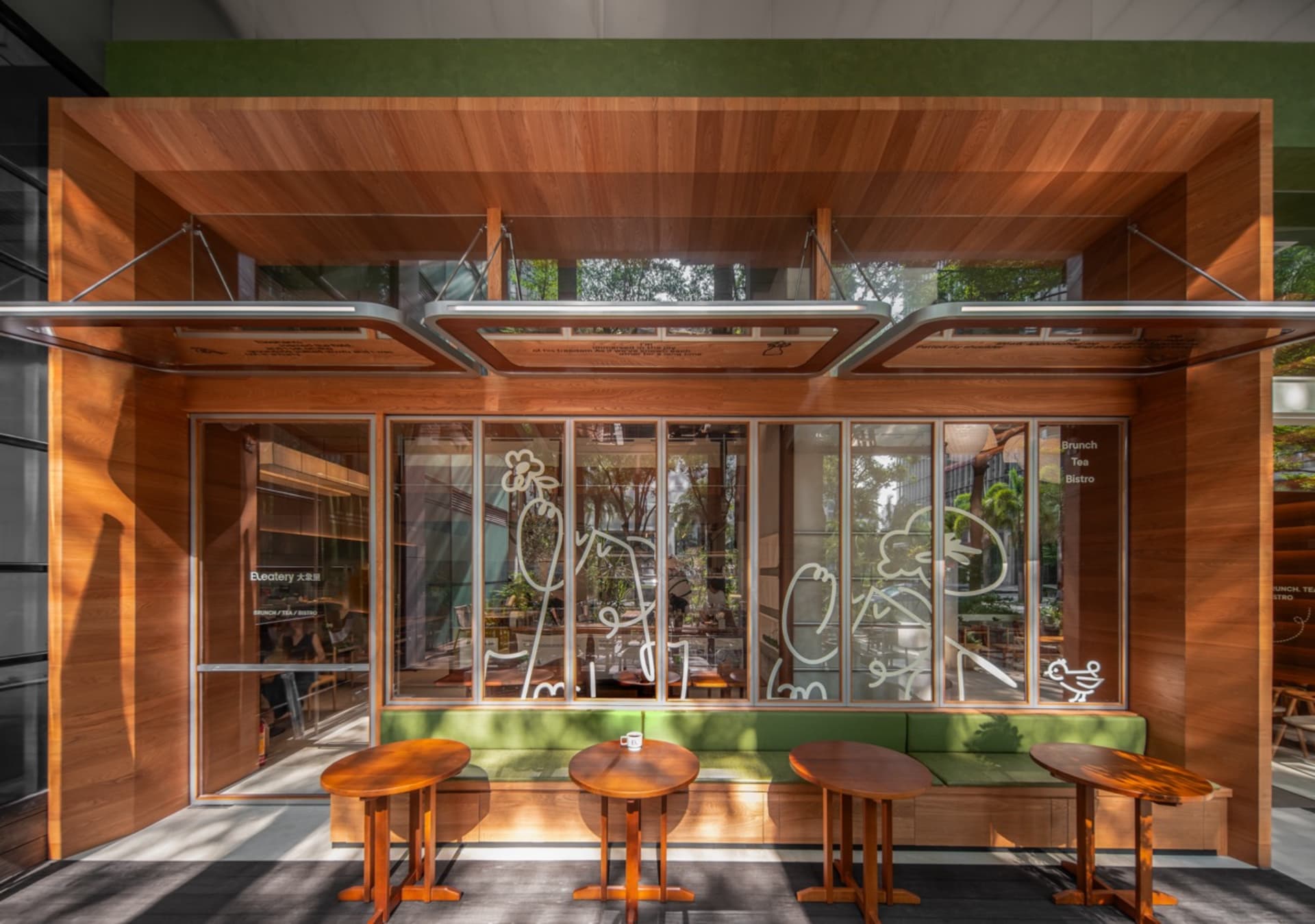 Modern outdoor cafe featuring wooden and glass elements with green accents