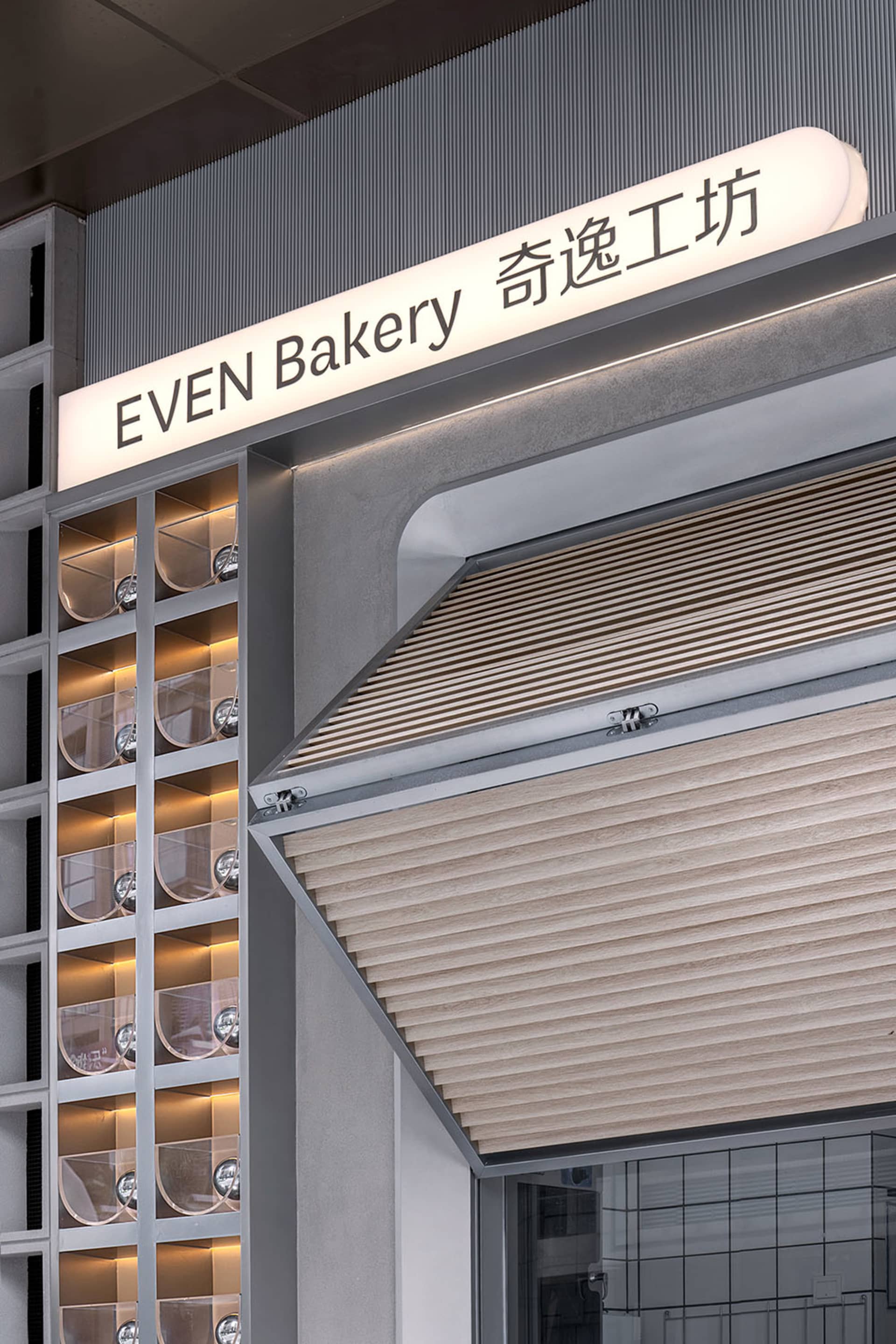 Even Bakery storefront with illuminated signage featuring metallic elements.