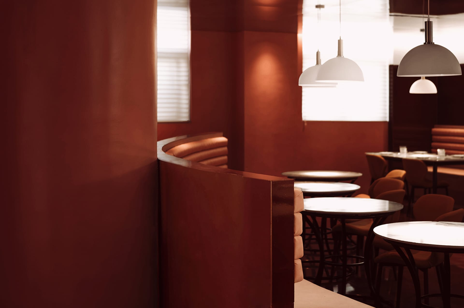 Interior of a modern industrial restaurant with red metallic walls and white pendant lights.