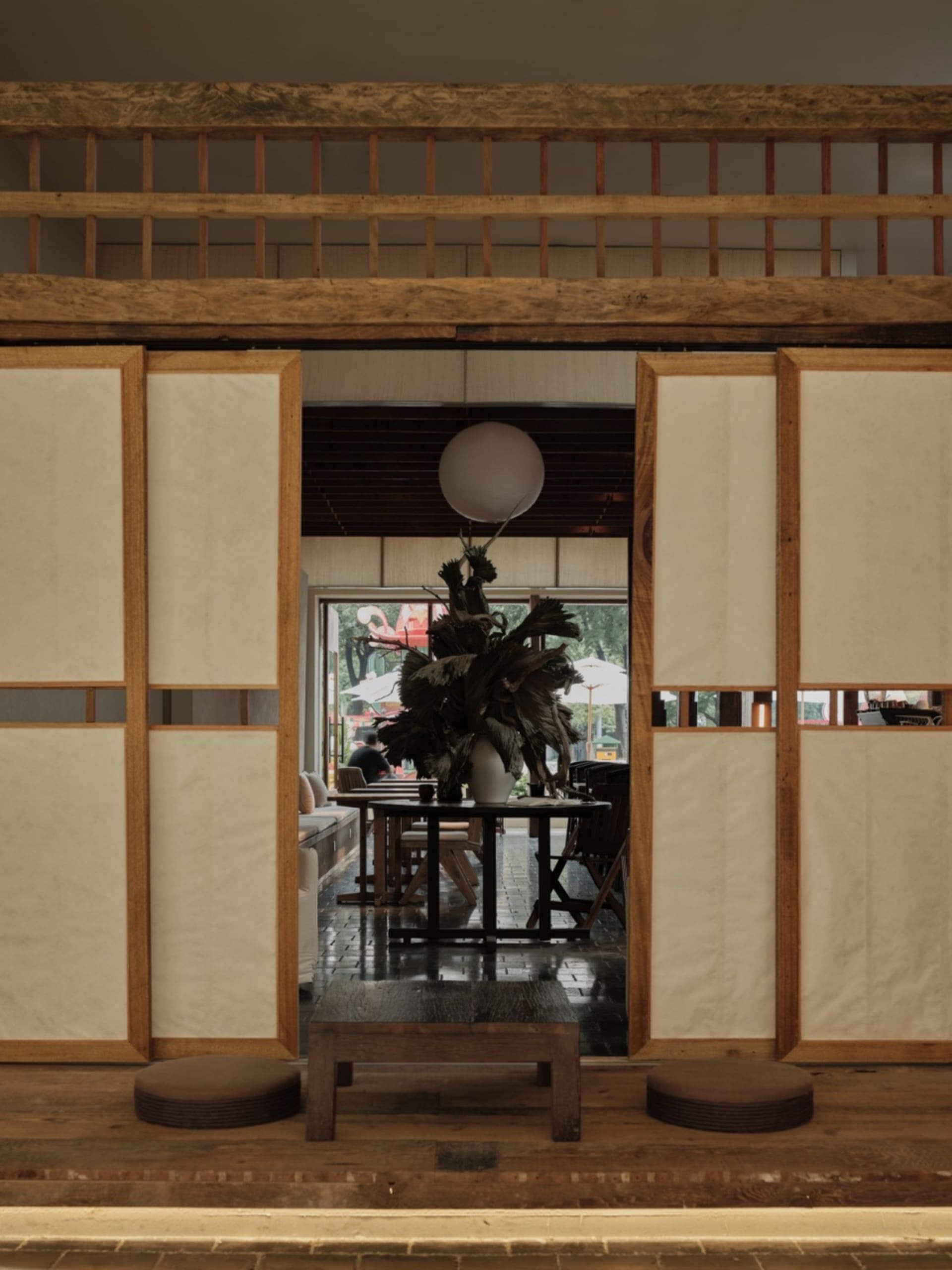 A traditional Japanese restaurant interior with paper walls, wooden beams, and a decorative plant on a round table.