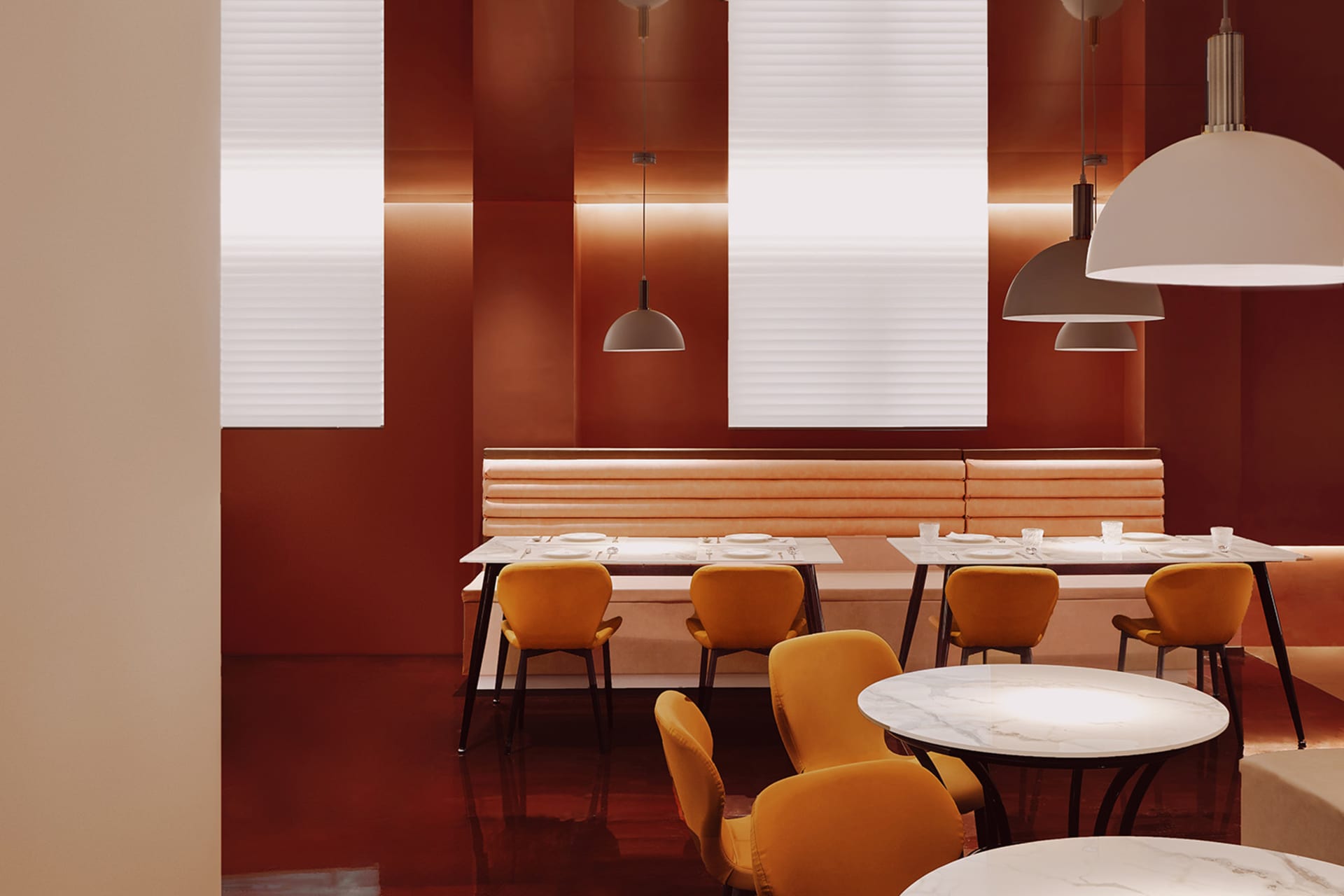 Industrial-style restaurant interior with orange upholstered benches and white marble tables.