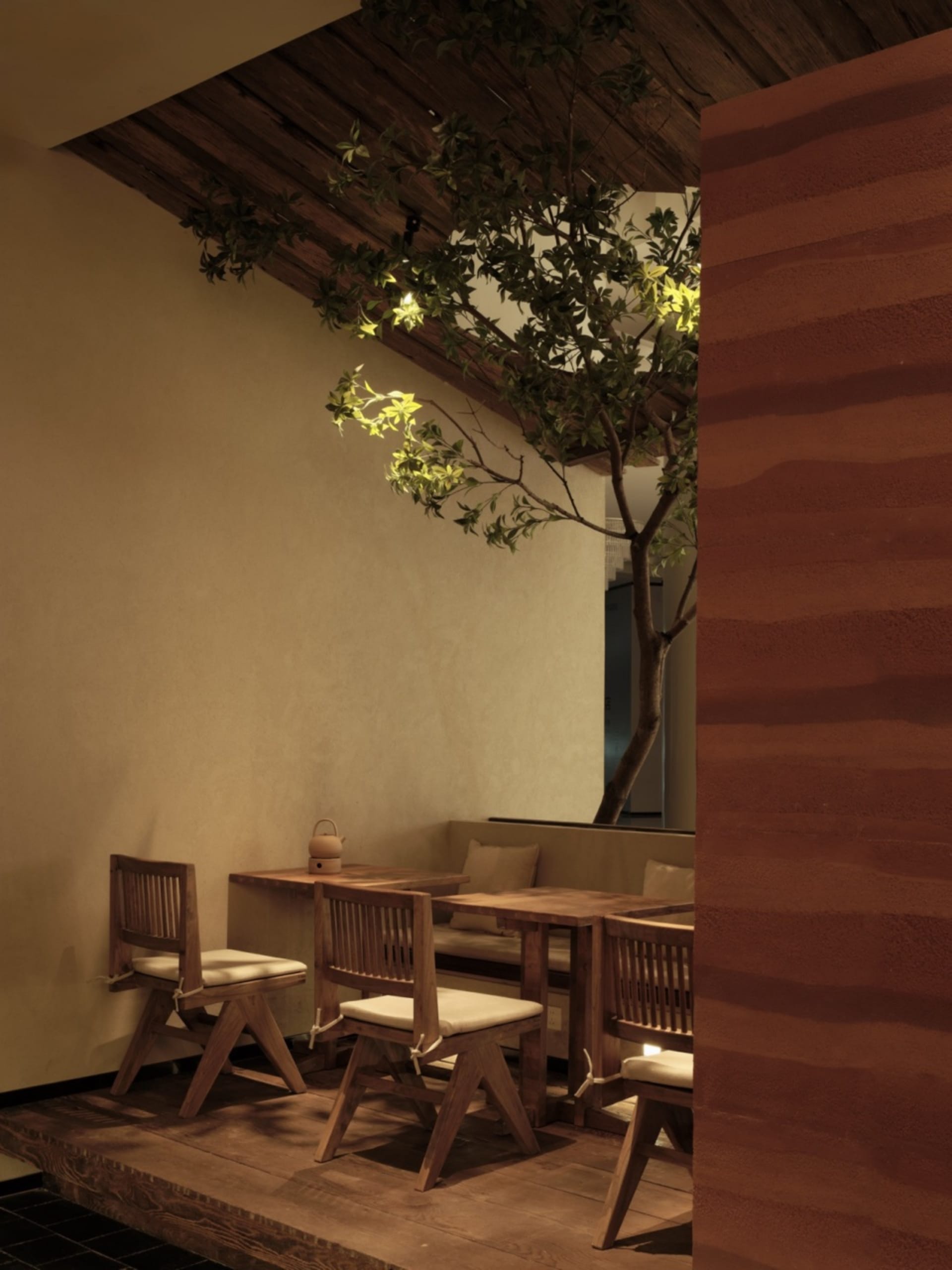 A minimalist restaurant interior featuring wooden furniture and a plant.