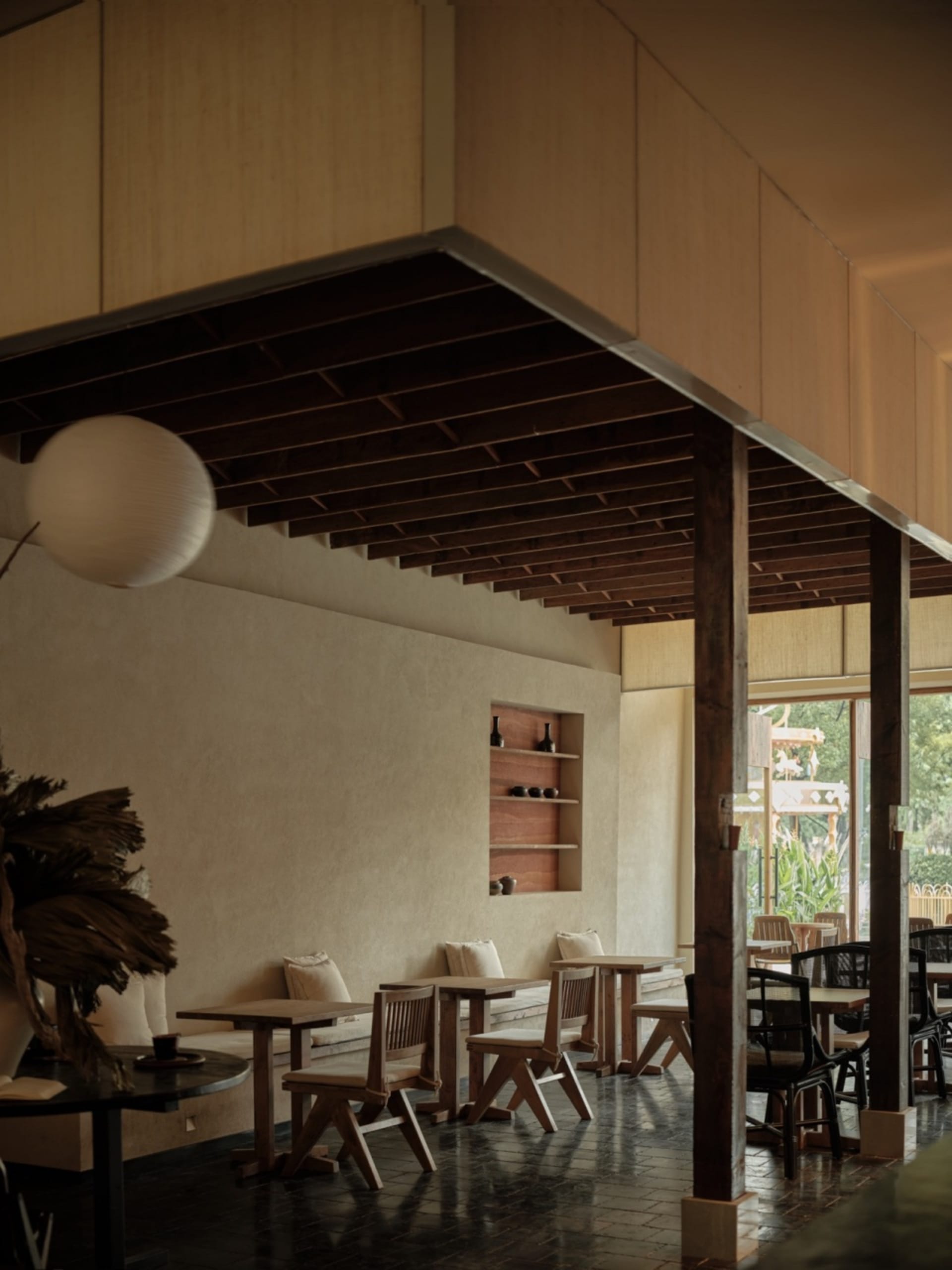 A modern cafe interior featuring wooden tables and chairs, with a ceiling adorned with wooden beams.