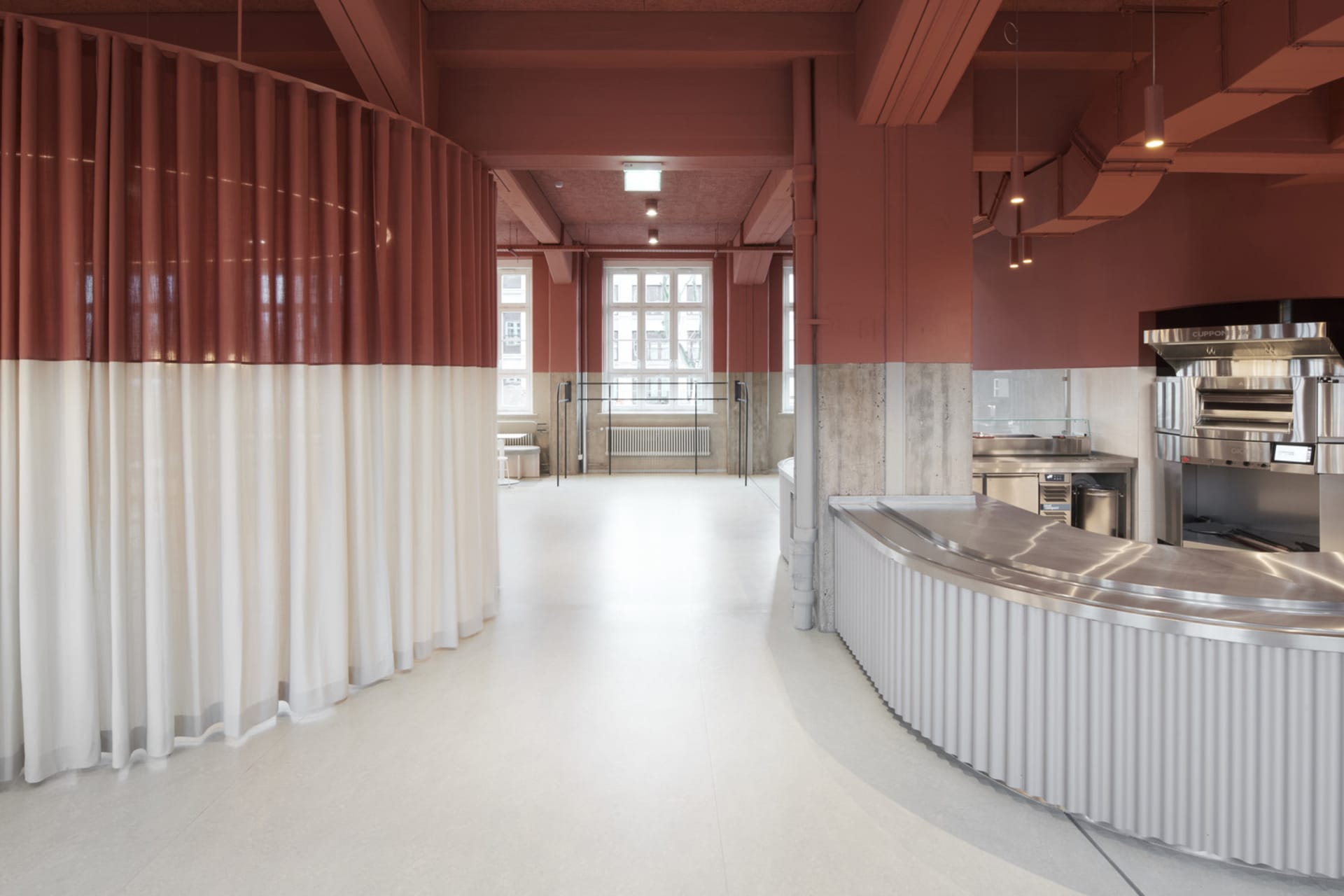 Modern cafeteria interior with red and white curtains, white flooring, and industrial-style materials.