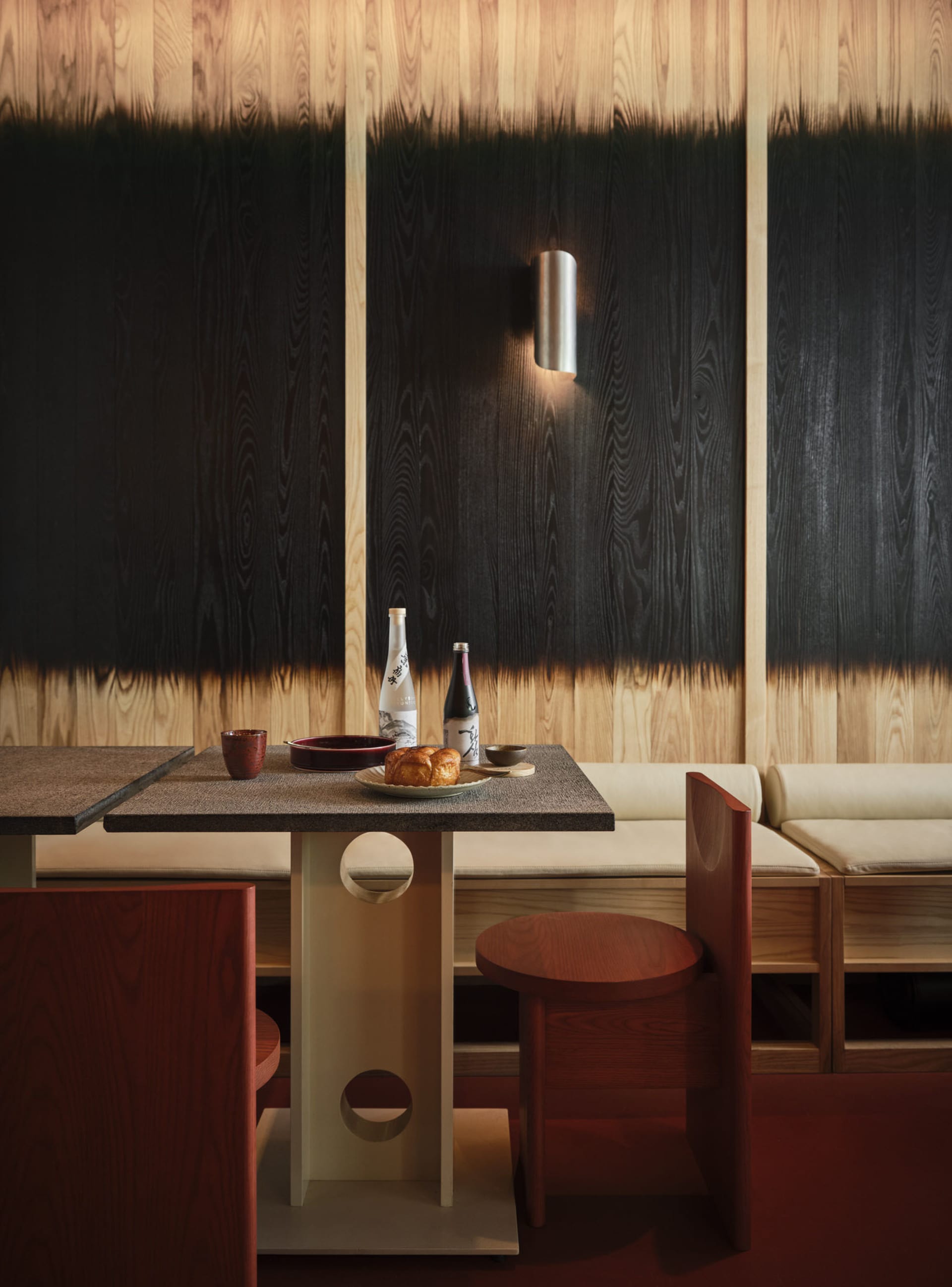 A modern restaurant interior with a wooden table and chairs, featuring a sleek design and minimalist aesthetics.