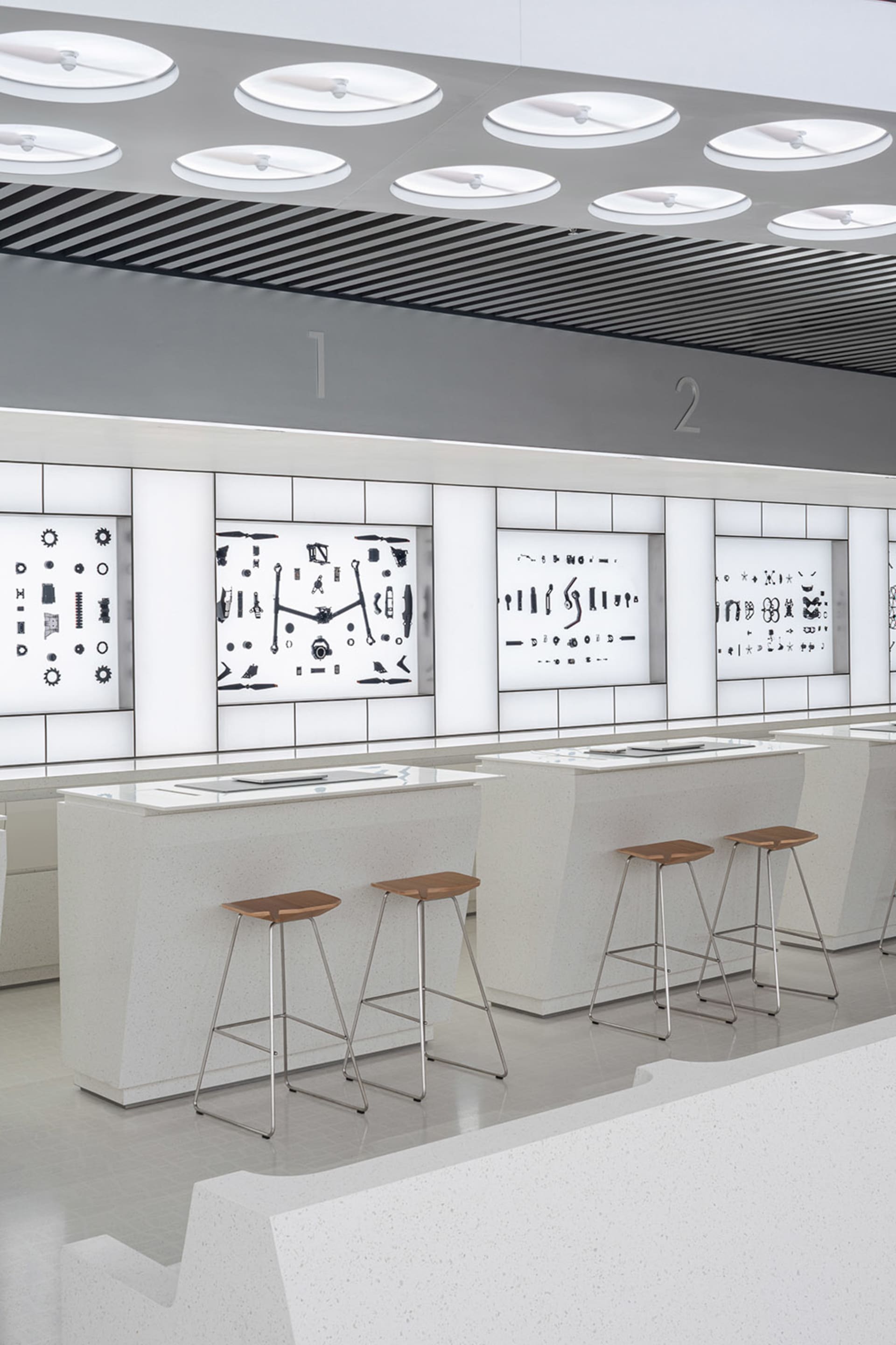 Industrial retail store area with metallic and wooden displays, white plaster counters, and stools.