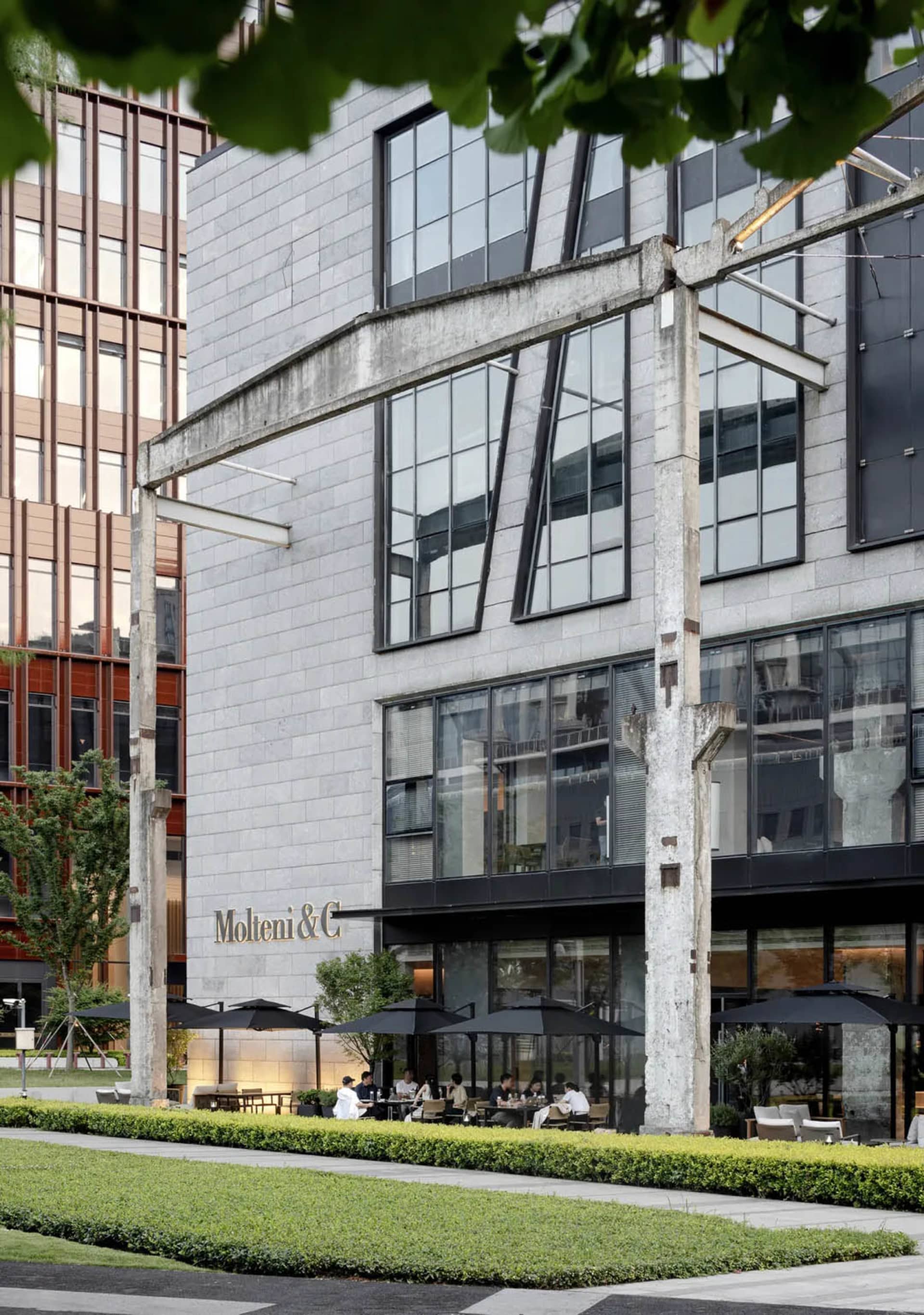 Modern restaurant exterior with concrete facade and large glass windows.