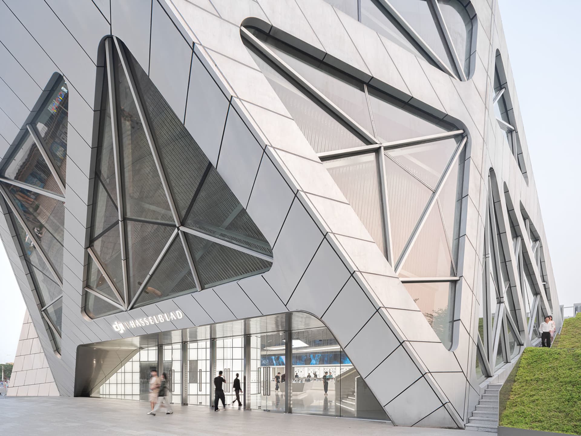 A modern building with a metal and glass facade, featuring angular geometric shapes.