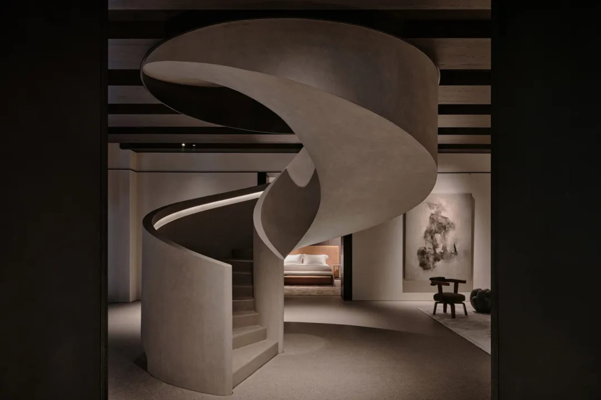 A minimalist bedroom connected by a spiral staircase made of concrete, featuring a bed with a beige headboard and a large abs