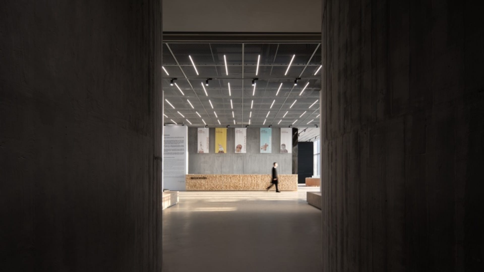 A modern industrial-style lobby with concrete walls and floors, featuring a minimalist design and contemporary lighting fixtu