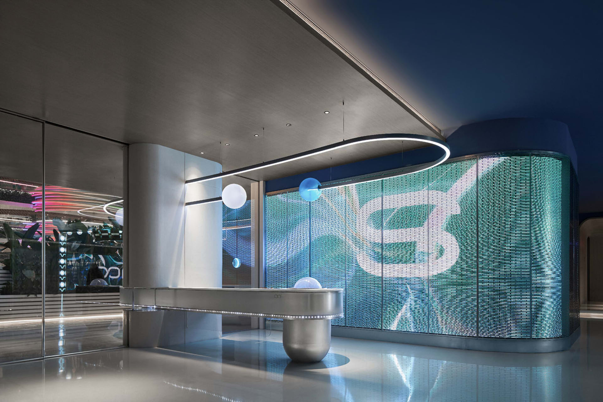 A modern office interior featuring a metallic reception counter and digital screen.