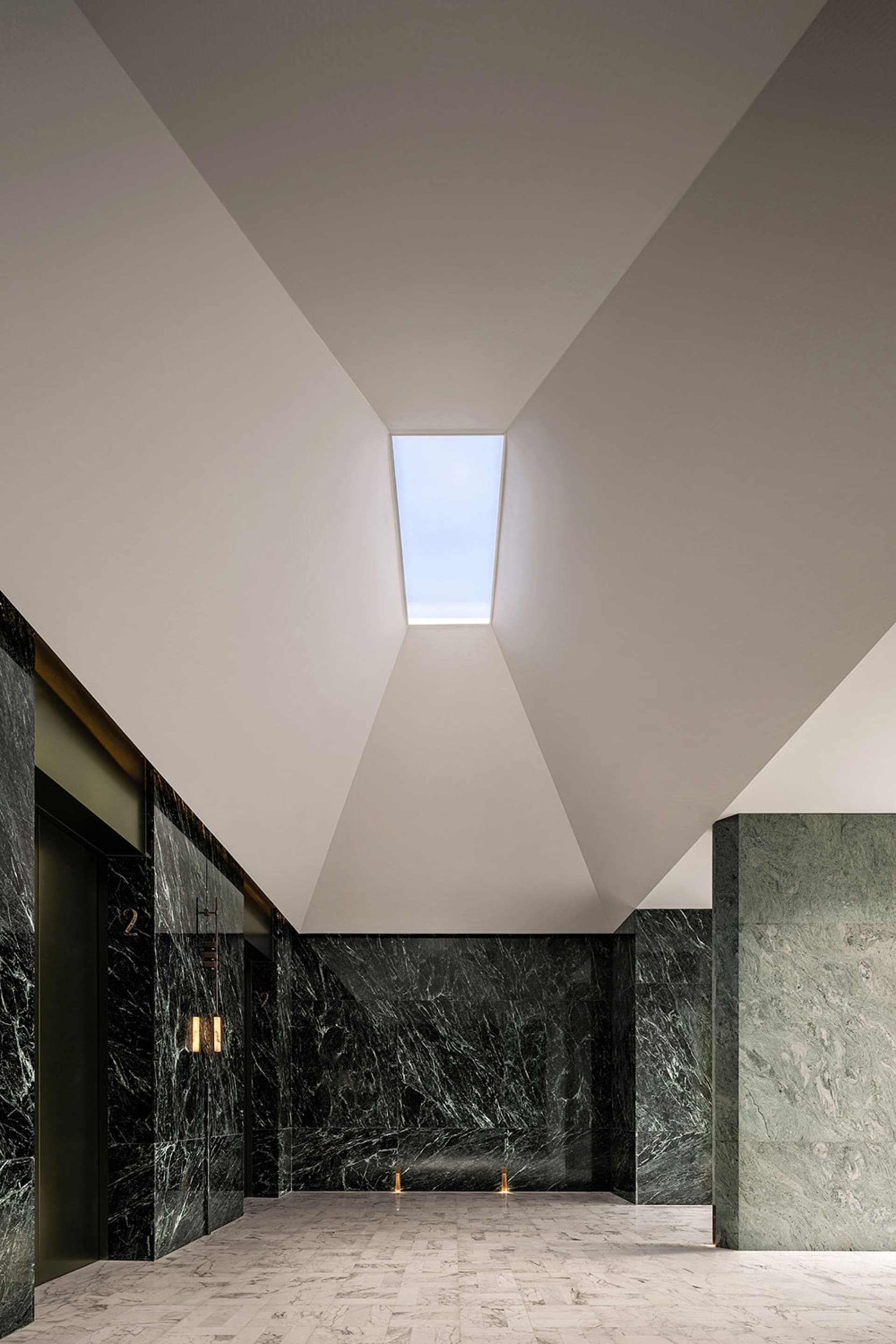 A modern lobby featuring marble floors and concrete walls.