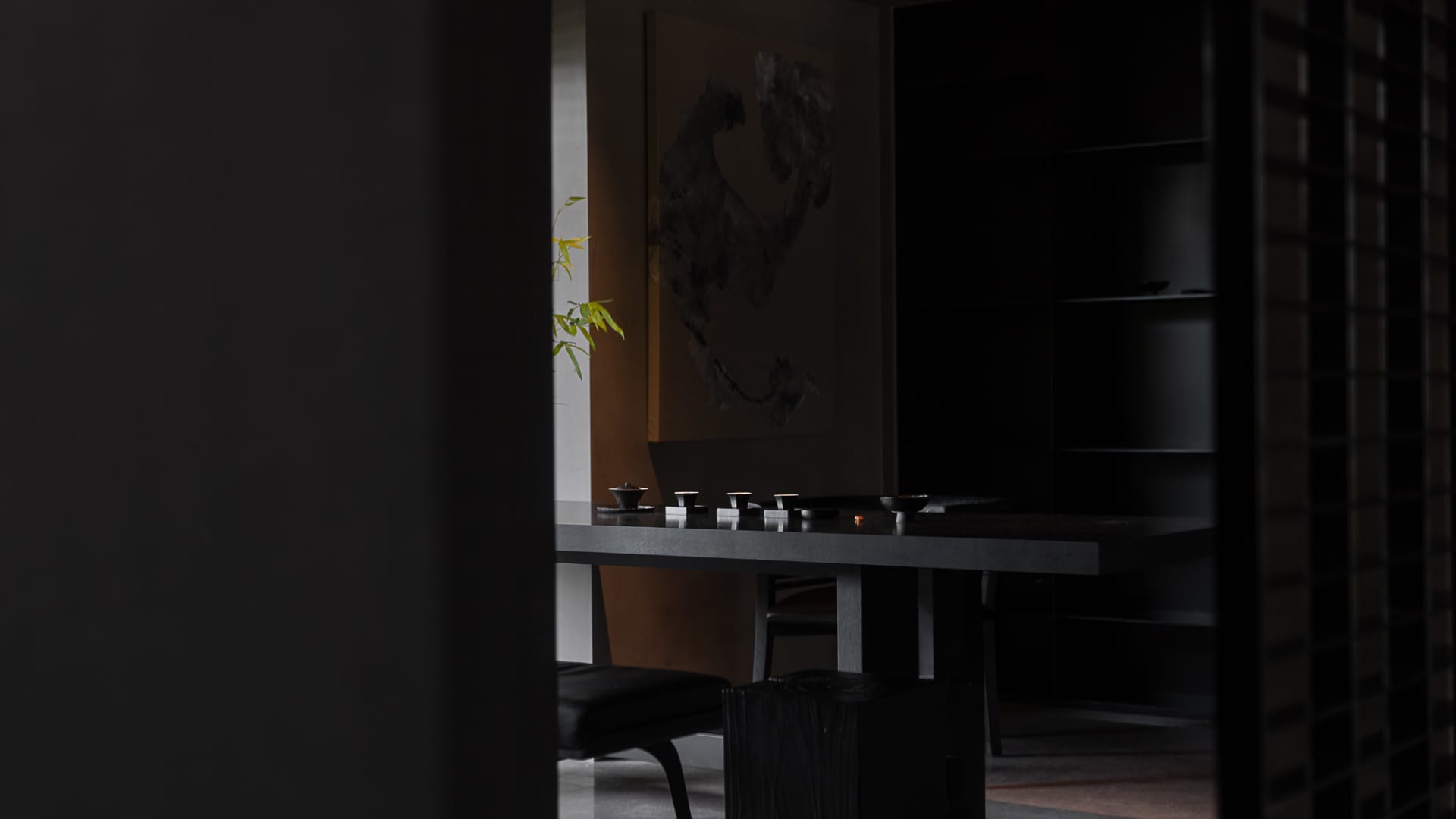 簡約茶室內擺放深色木質家具，以及簡單的茶壺與茶杯組合。