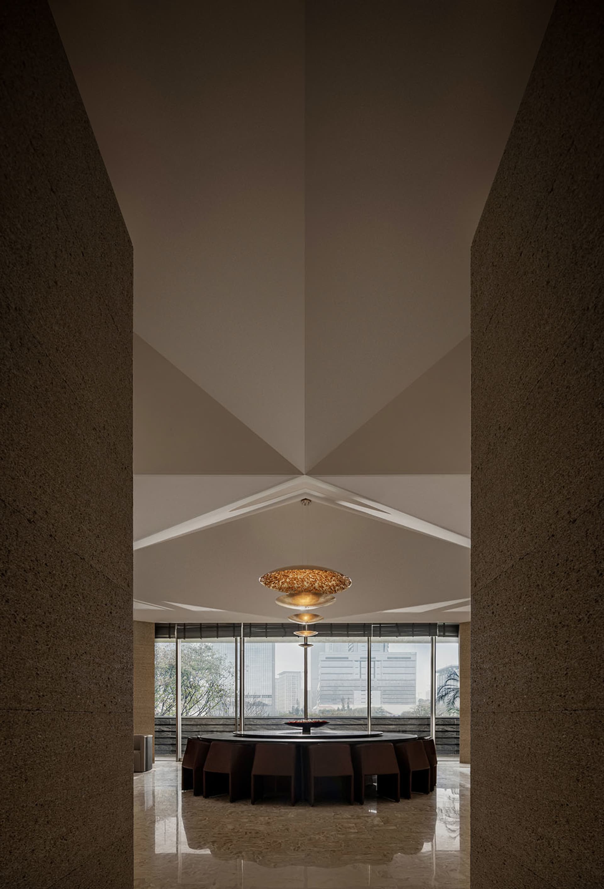 Modern dining room featuring a concrete ceiling and walls with a round dining table surrounded by chairs.