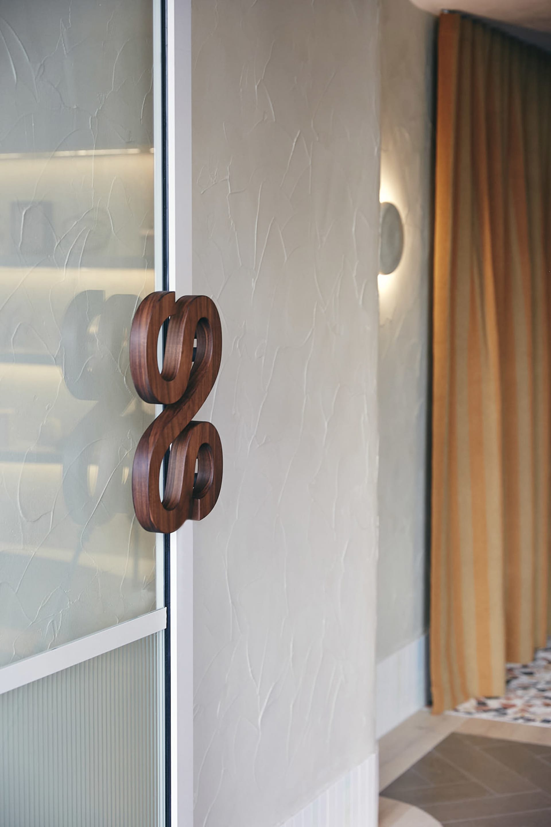 Close-up shot of a modern wooden door handle on a frosted glass panel.